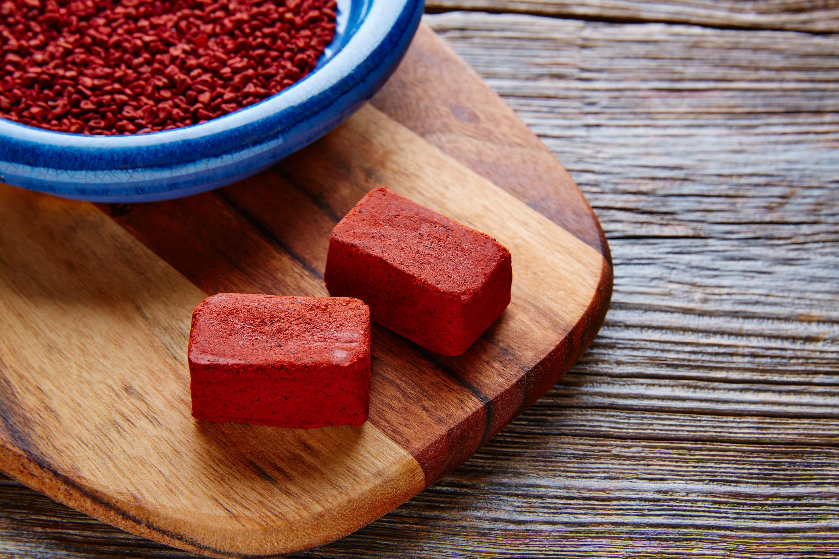 Achiote powder and blocks on wooden board