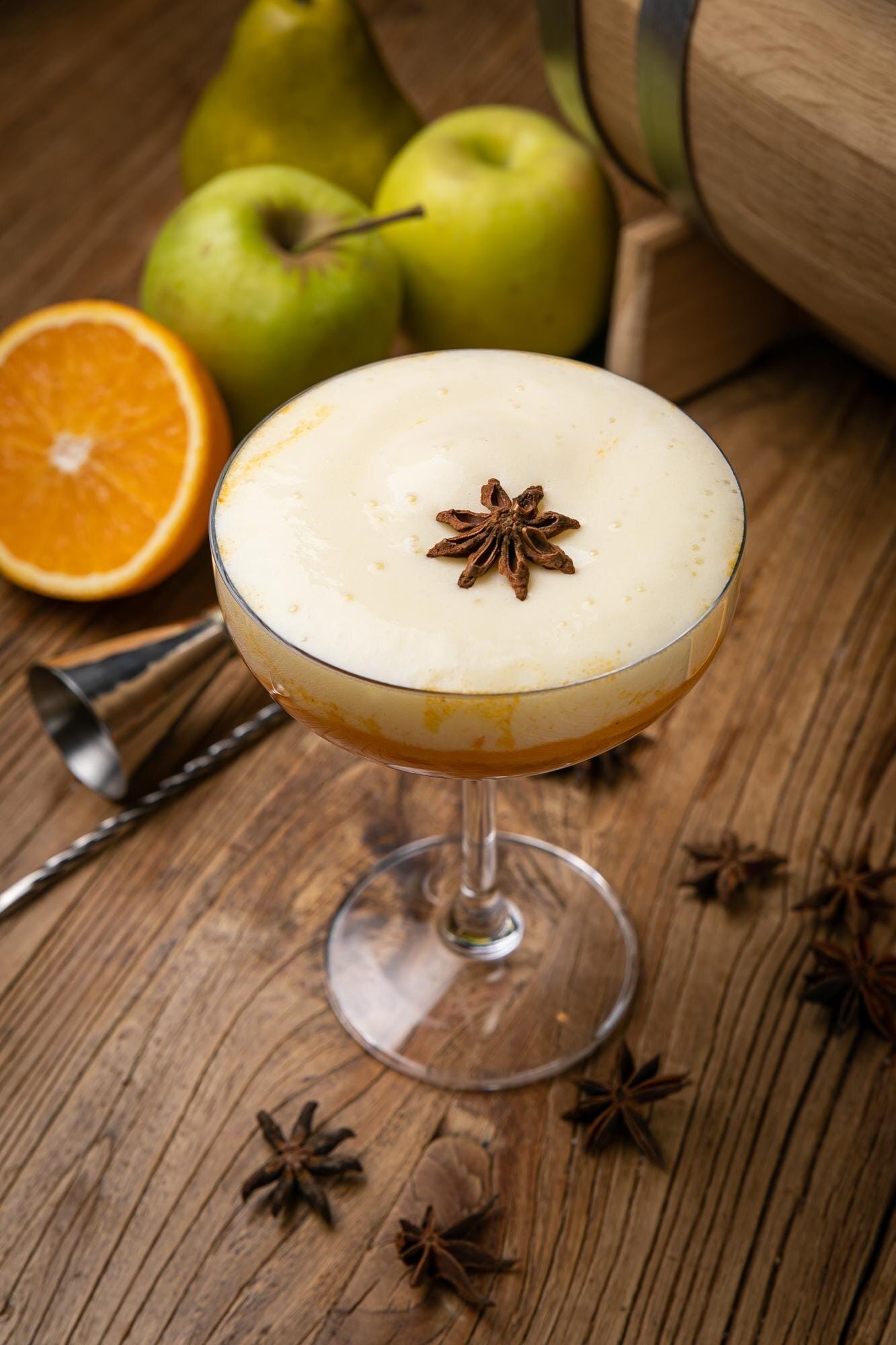 Apple cider cocktail in a coupe glass with apples and star anise