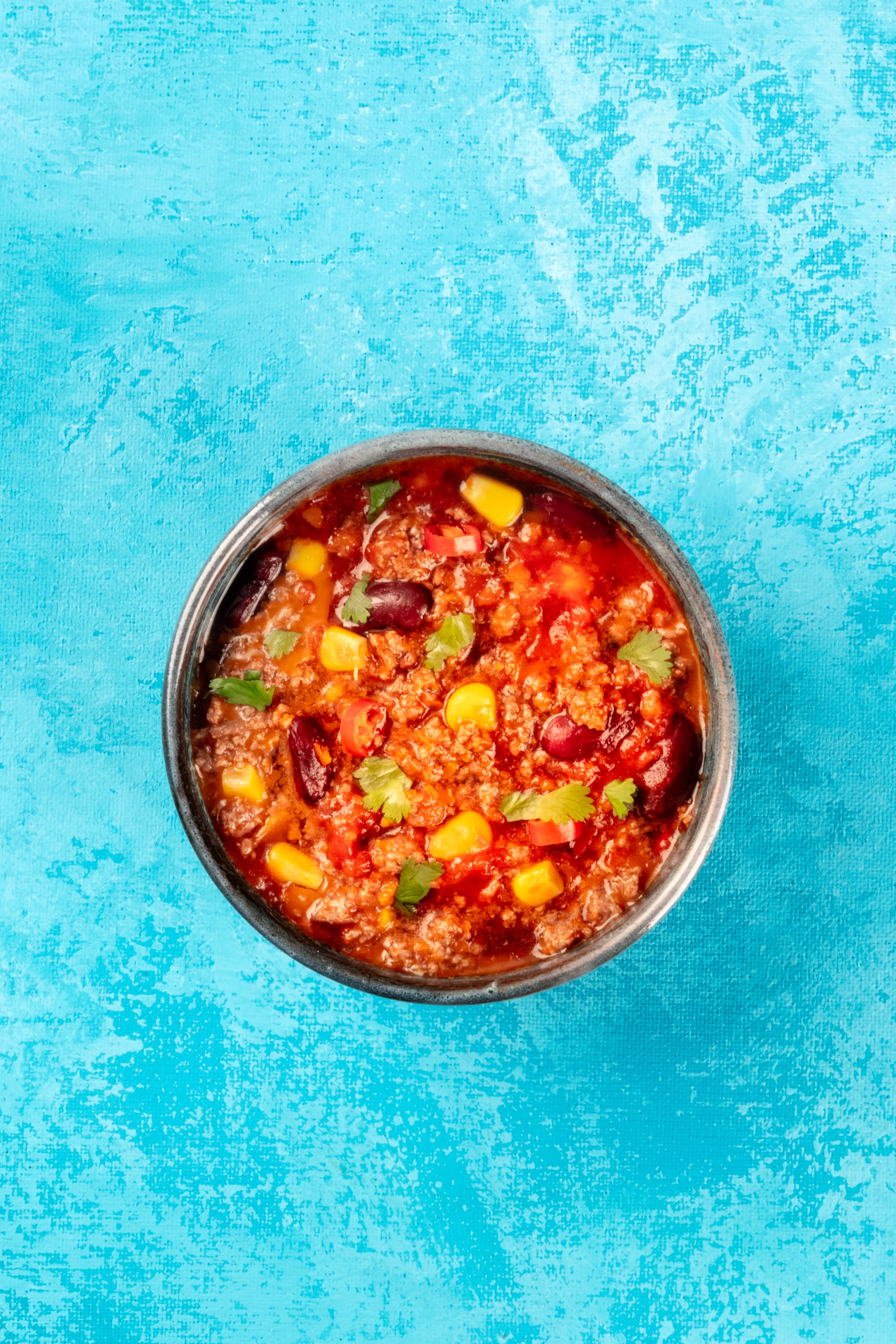 Bowl of chili con carne on a blue background