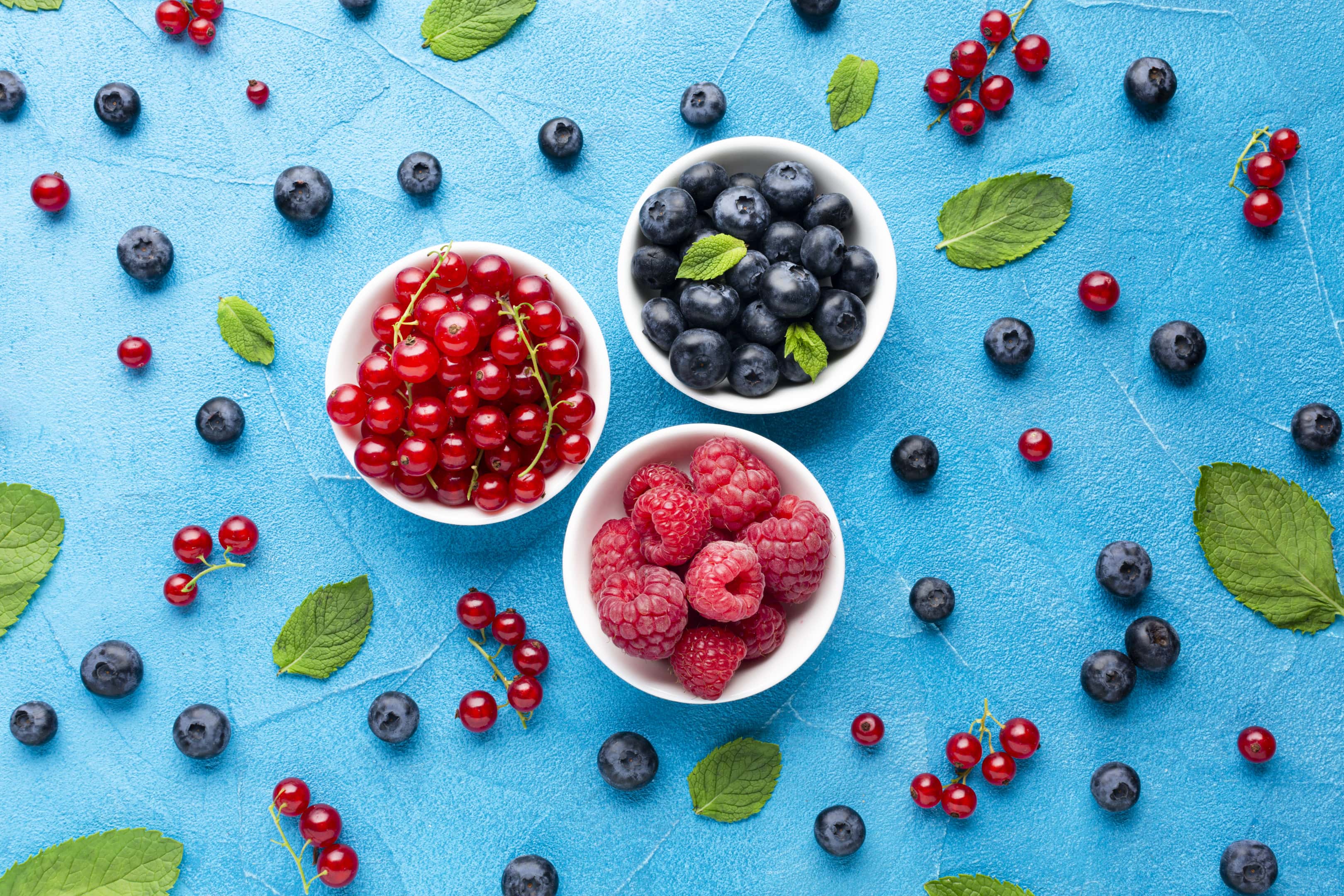 Bowls of fresh berries on blue background