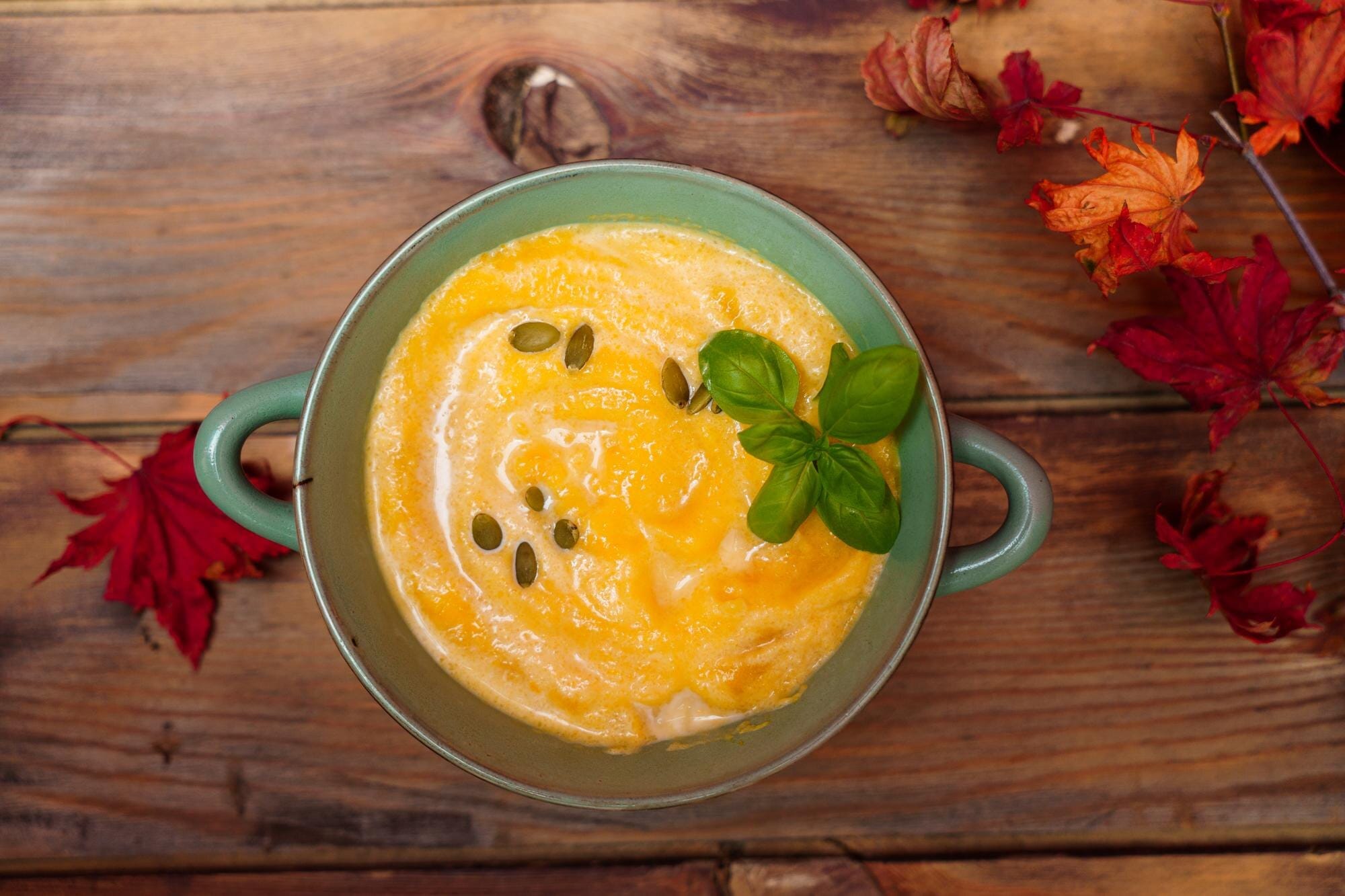 Bowl of butternut squash soup garnished with pumpkin seeds and basil