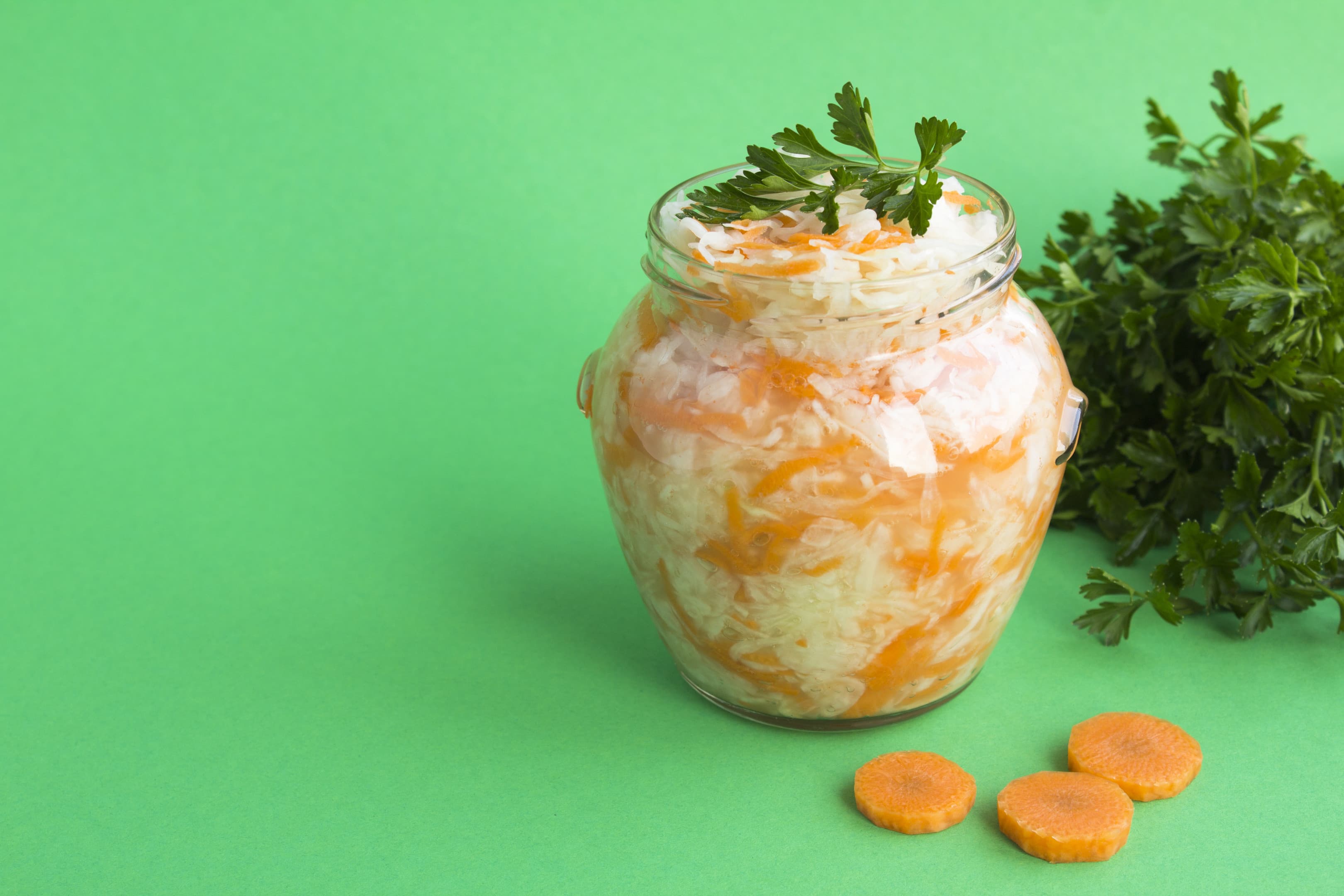 Caribbean pikliz in glass jar on green background