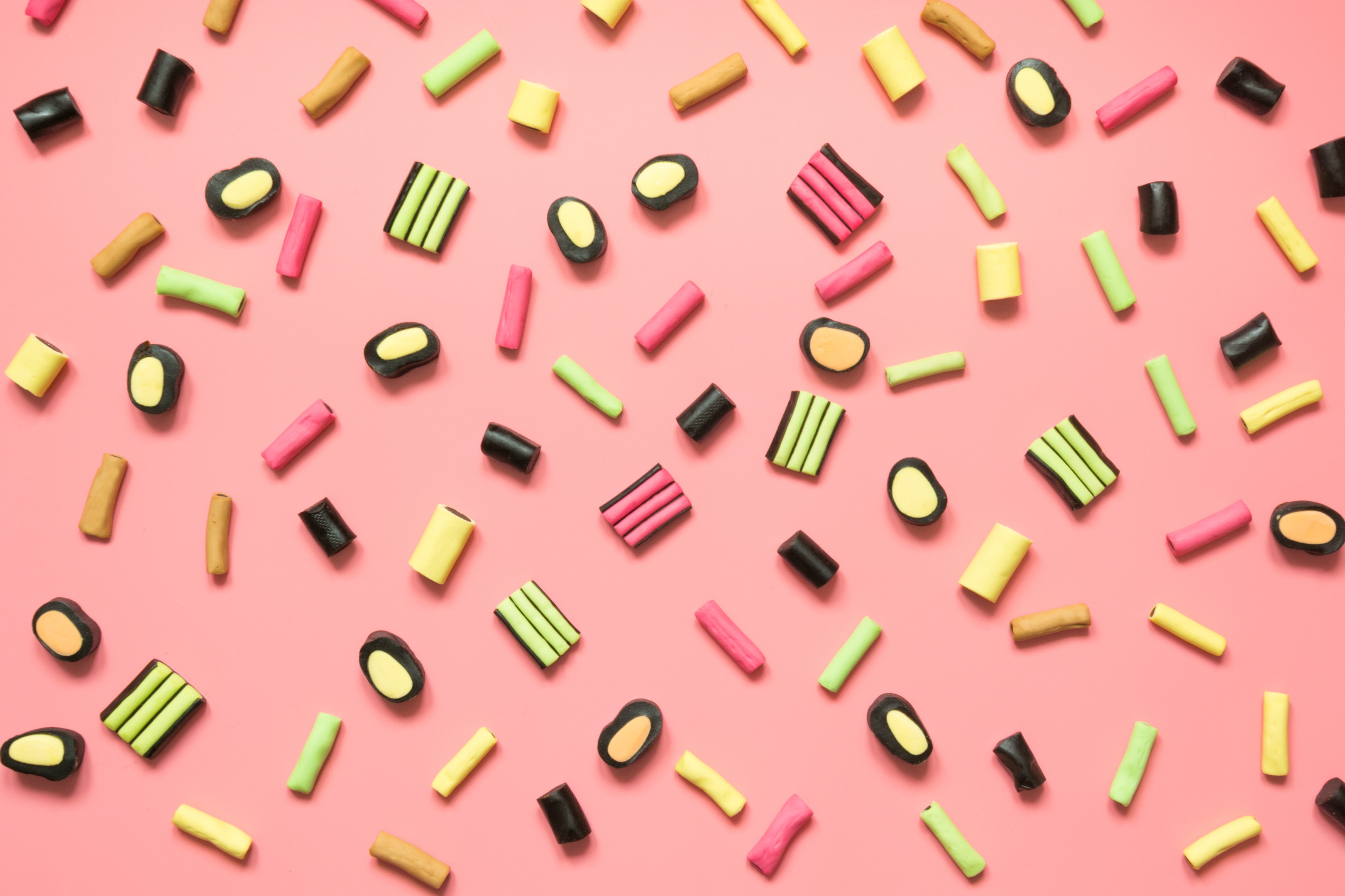 Colorful lollipop and licorice candy assortment on pink background