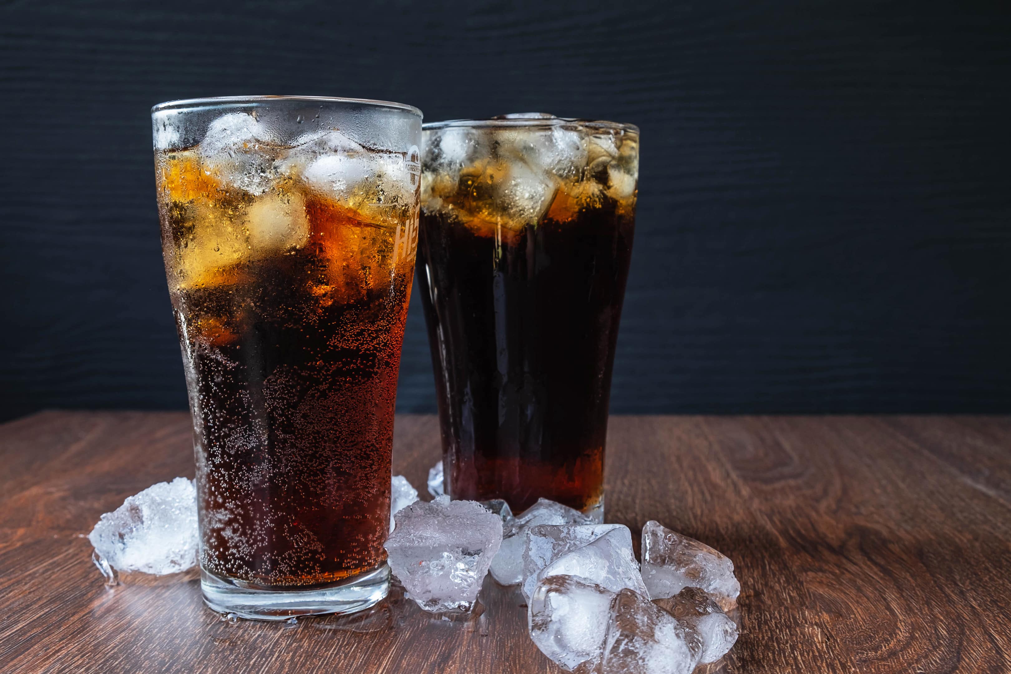 Diet cola soda glass with ice cubes on wooden table