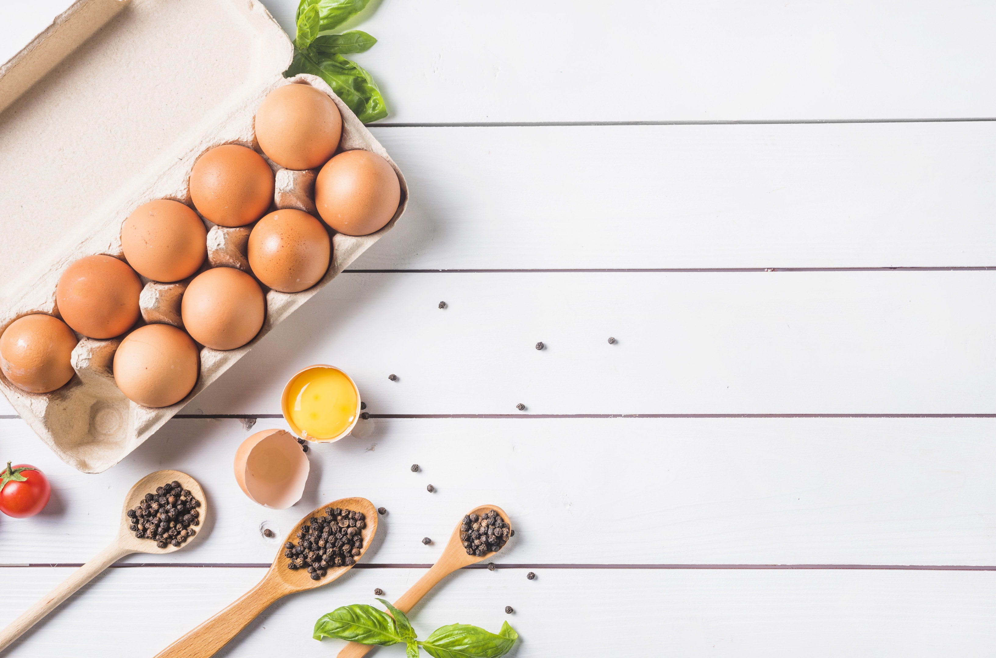 Eggs with peppercorn in wooden spoon on wooden table