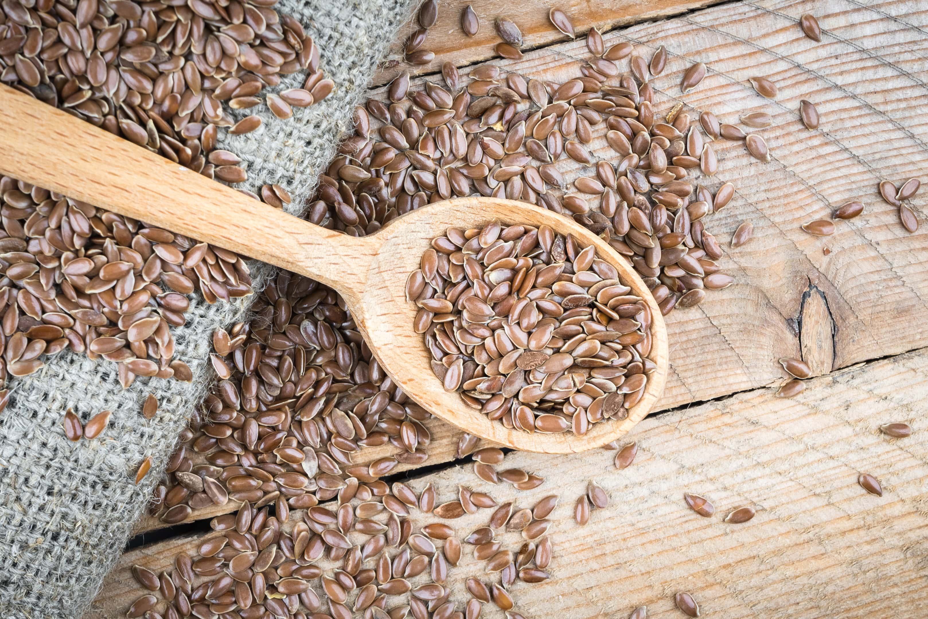 Flax seeds in wooden spoon on wooden table