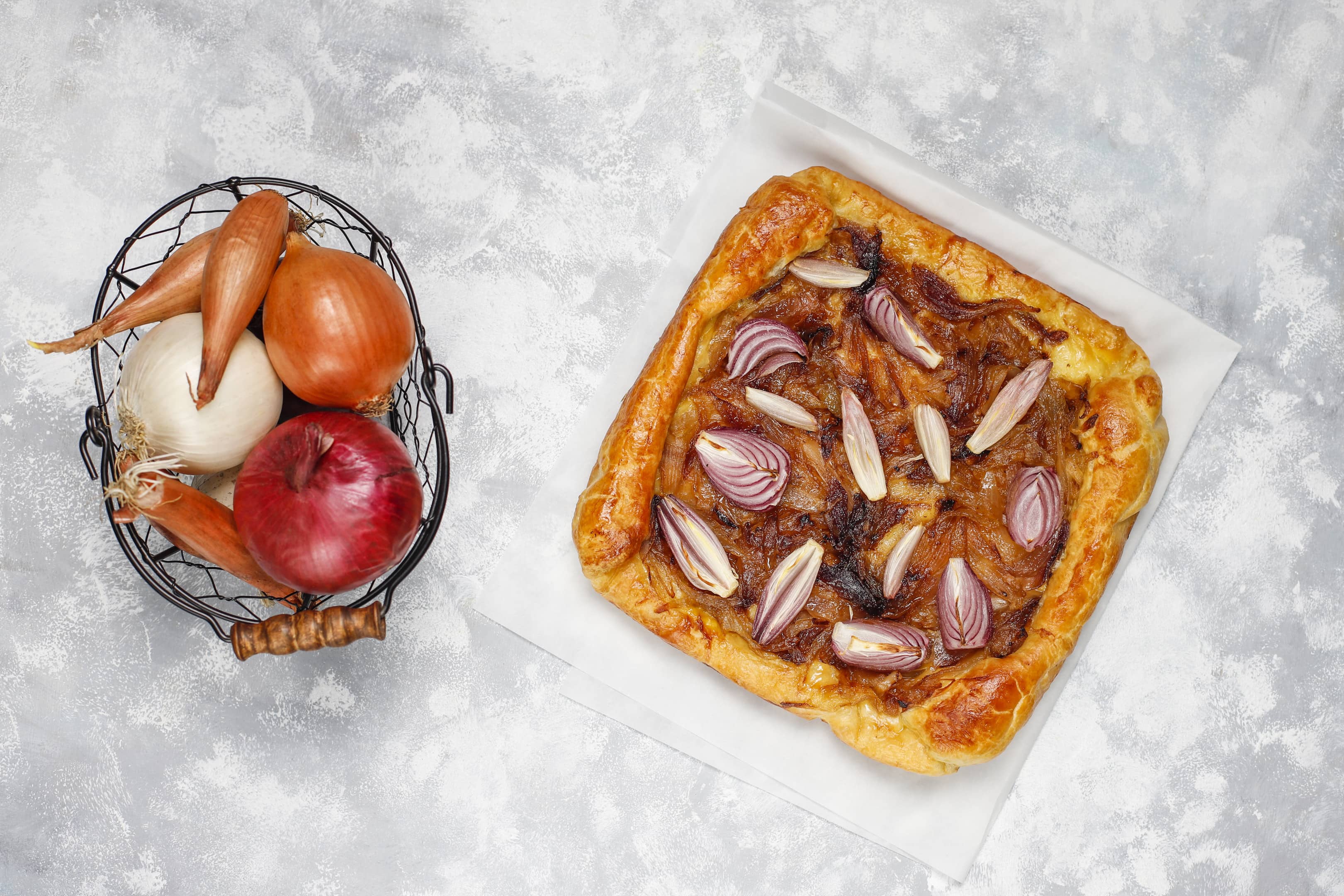 French style onion pie galette with puff pastry and various onions — shallot, red, white and yellow onions
