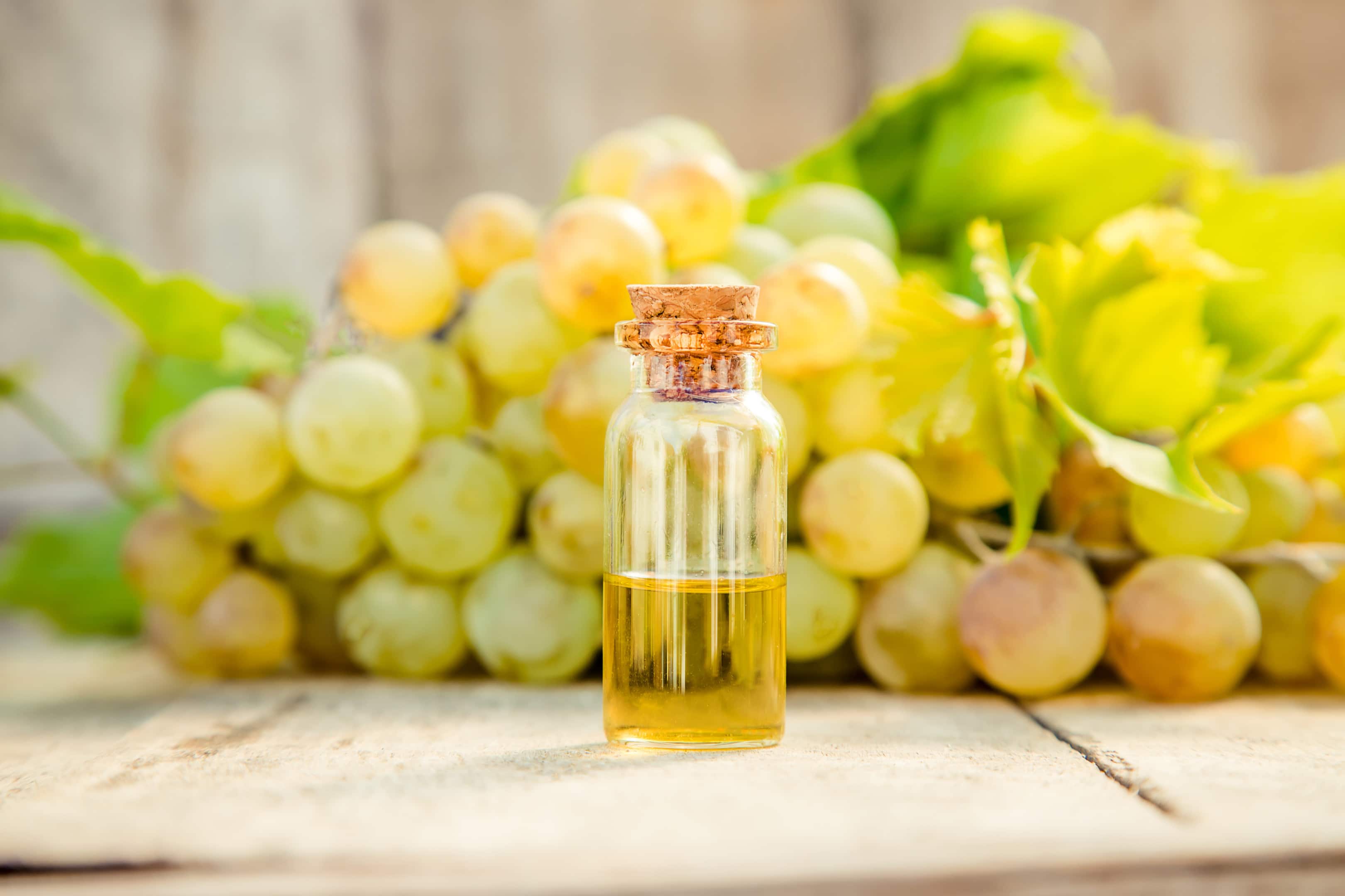 Grape seed extract in a small glass bottle with fresh grapes