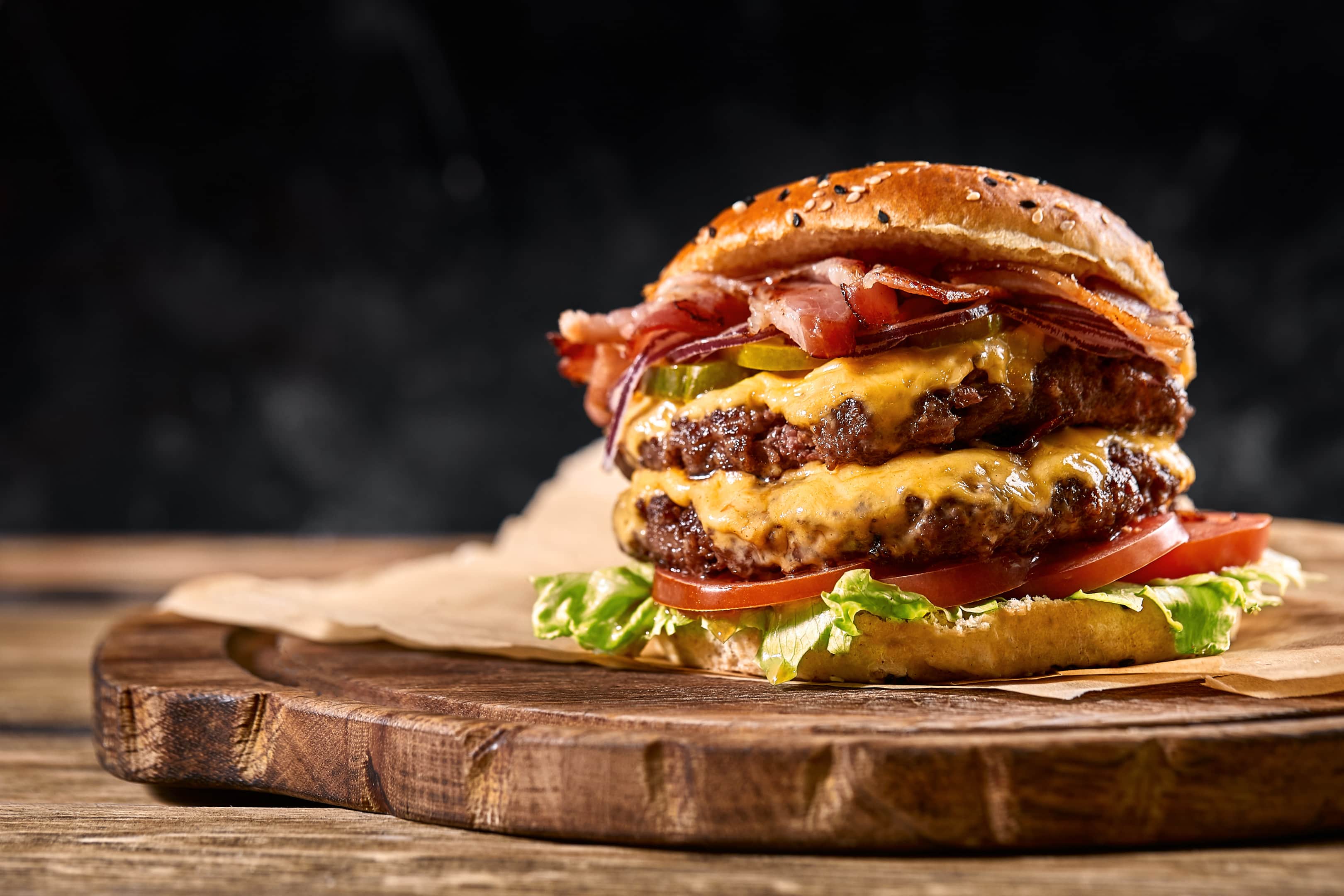 Juicy american burger cheeseburger with two beef patties and sauce on wooden board
