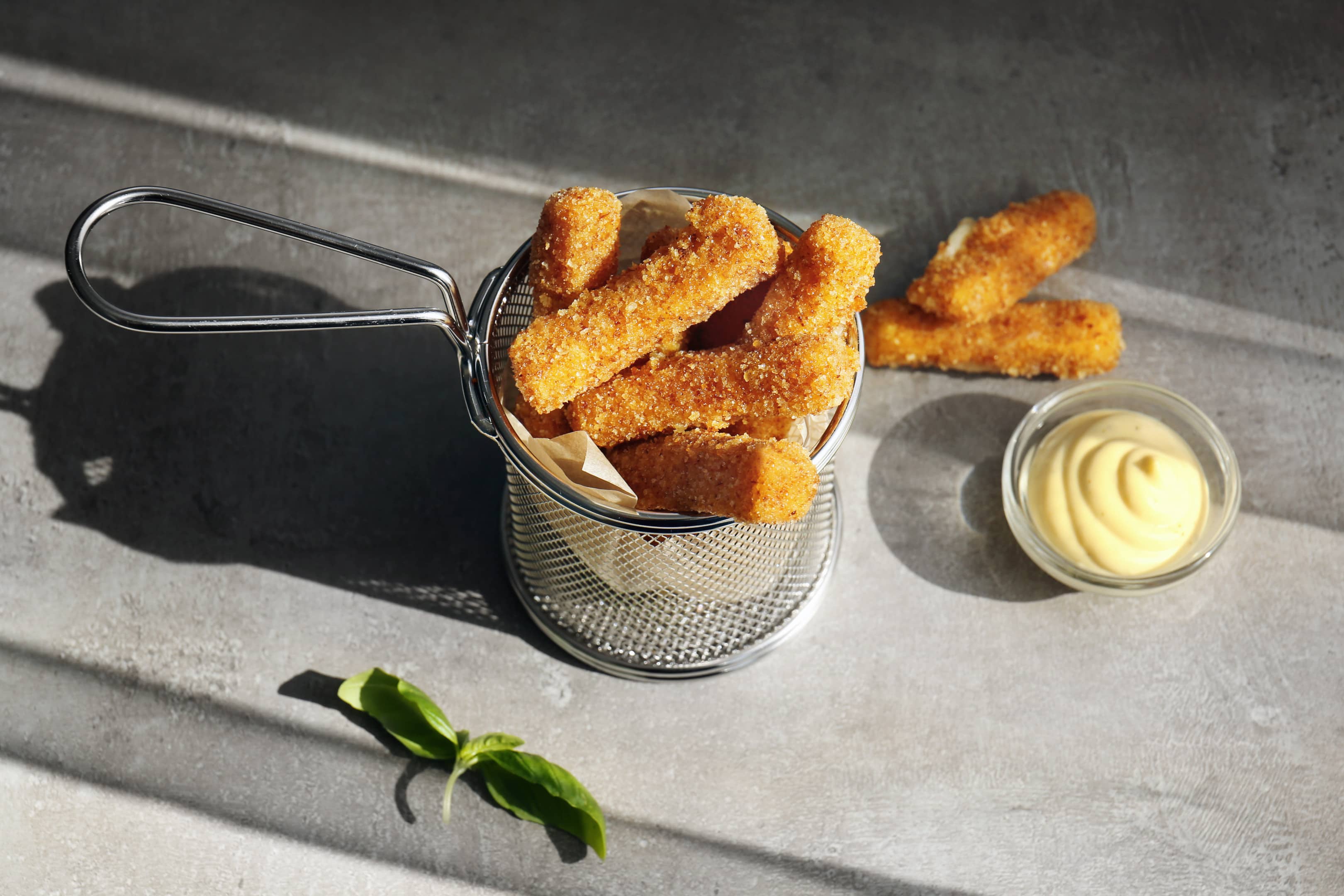 Metal basket with cheese sticks on table