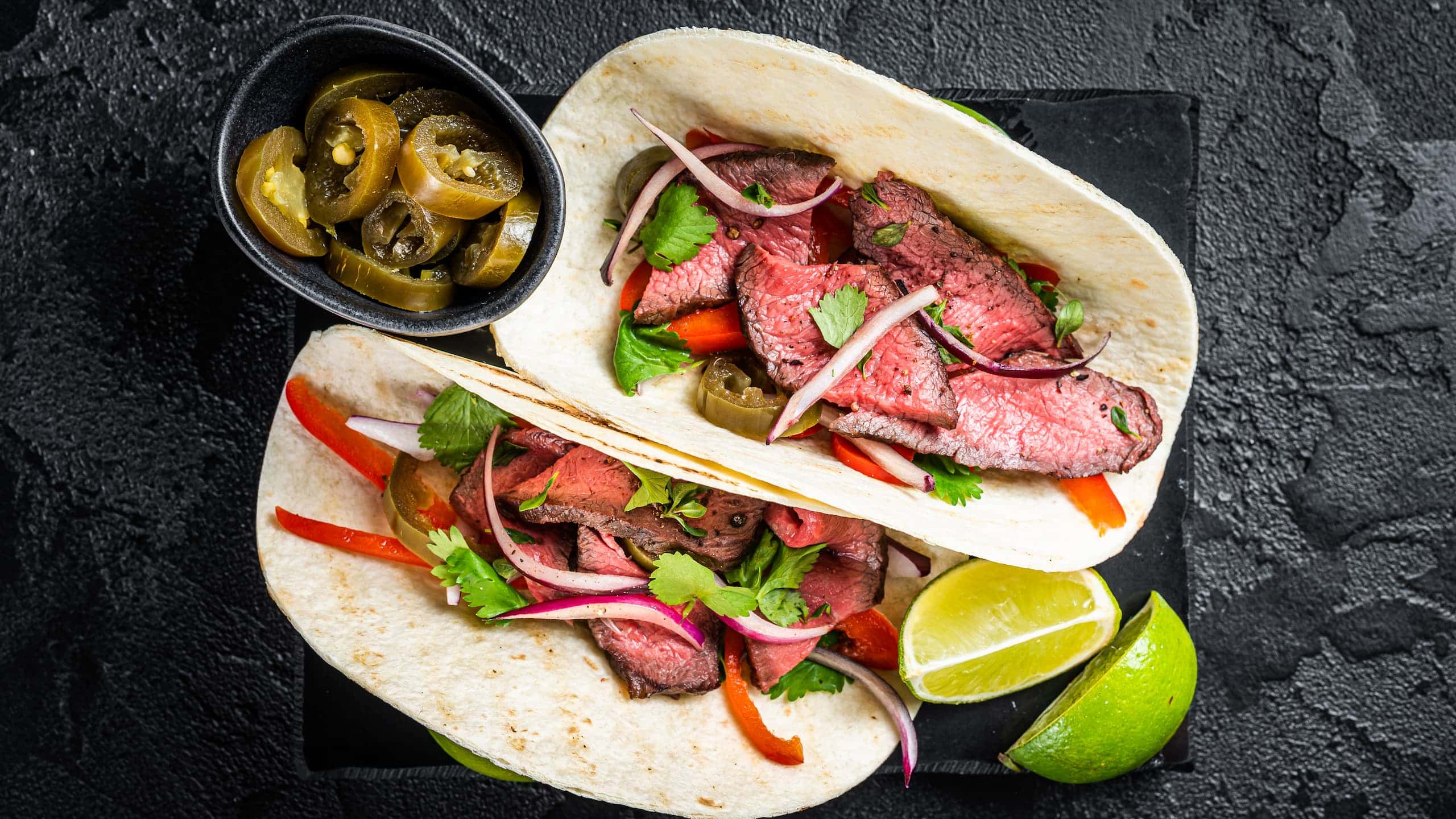 Lupe Tortilla fajita with meat, cilantro, jalapenos, and onion