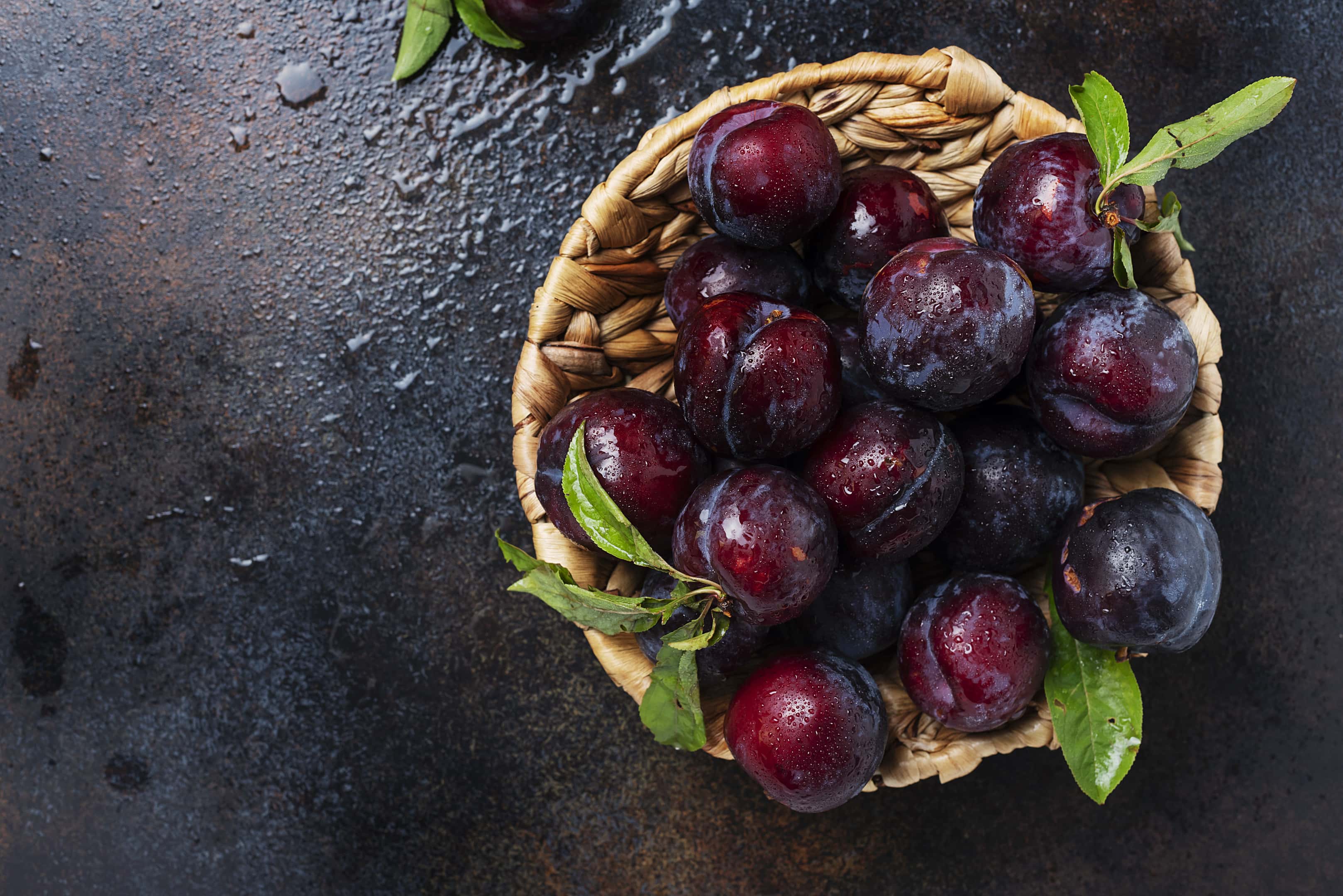 Ripe plums in wooden bowl