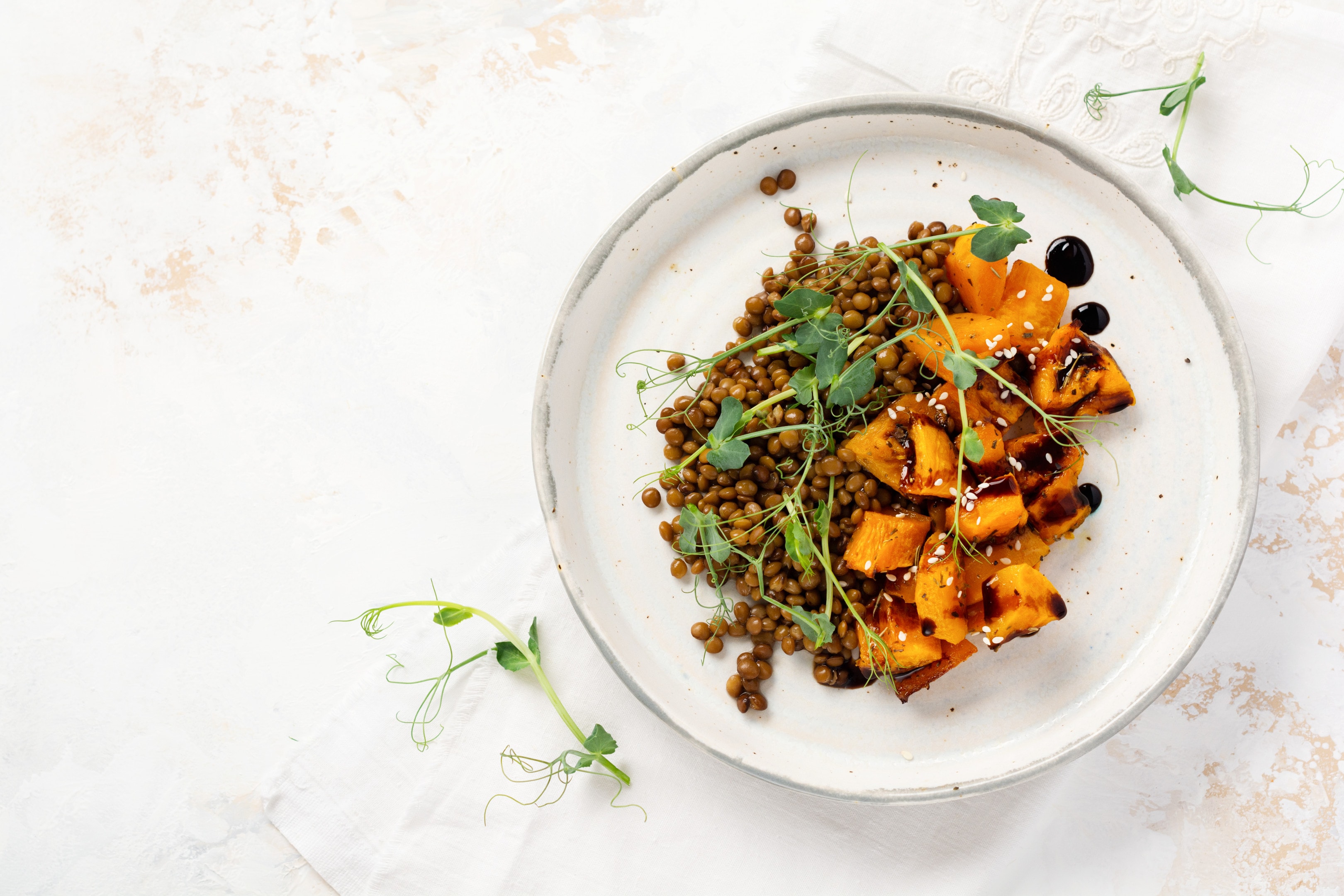 Salad with baked pumpkin, lentils and balsamic dressing garnished with peas microgreens