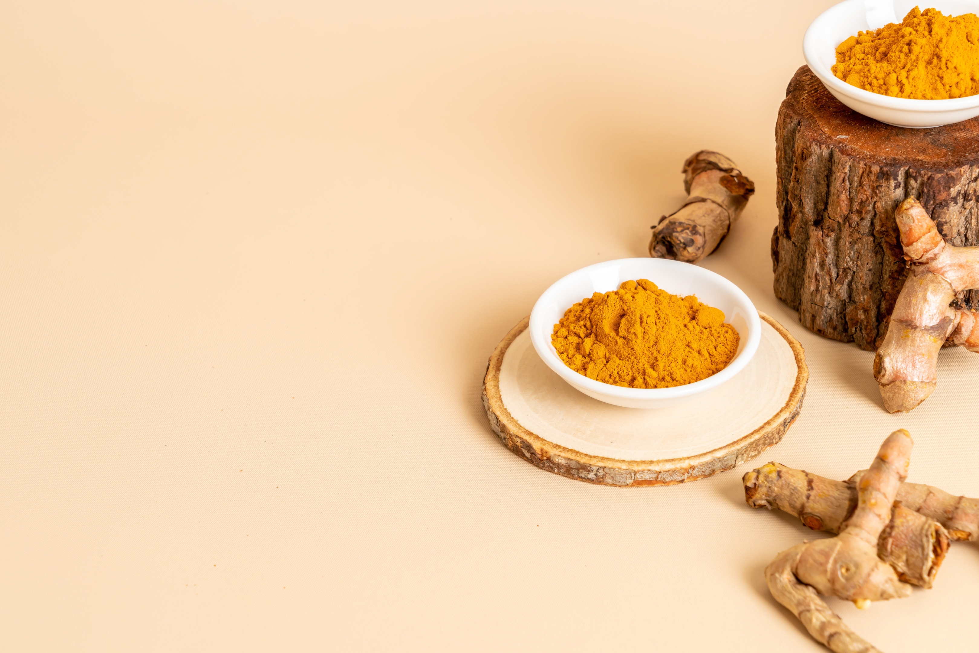 Turmeric powder and fresh turmeric on pastel background