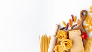 Mix of uncooked pasta and hard cheese on white background