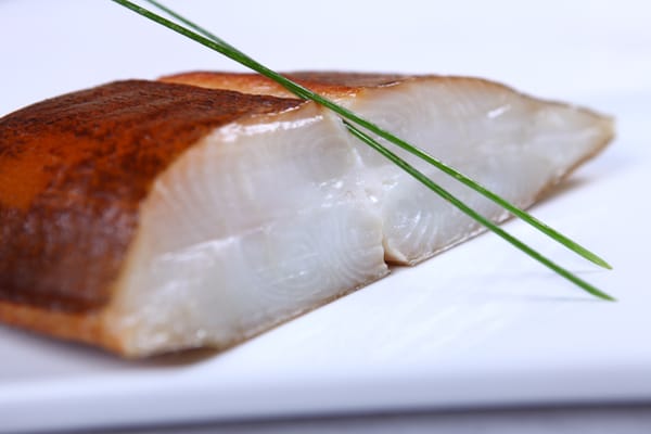White fish fillet garnished with spring onion and lime