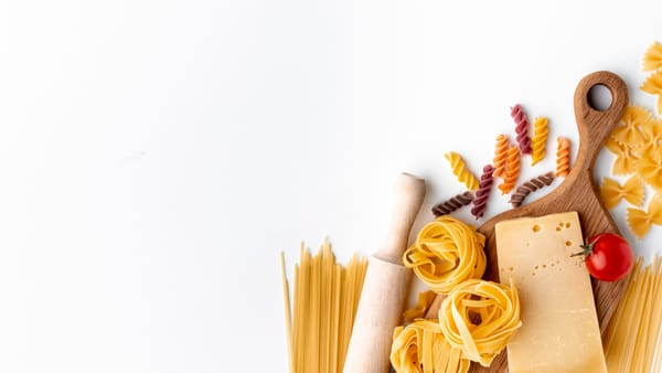Mix of uncooked pasta and hard cheese on white background