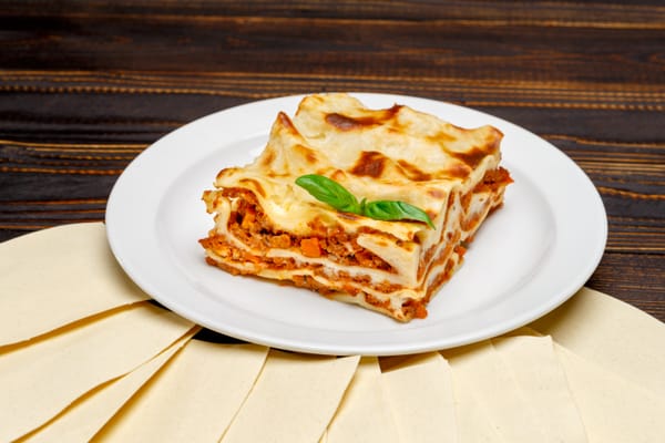 Slice of lasagna on a wooden surface