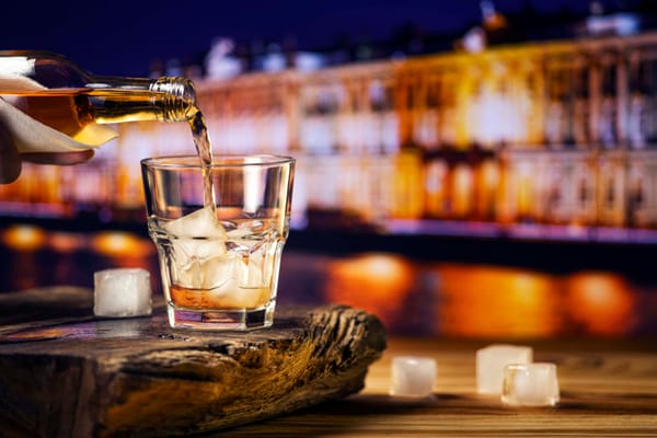 Pouring whiskey into glass with ice