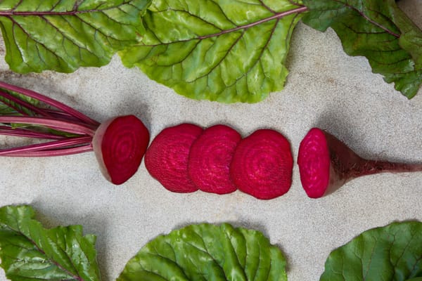 Raw beetroot sliced with leaves on rustic board