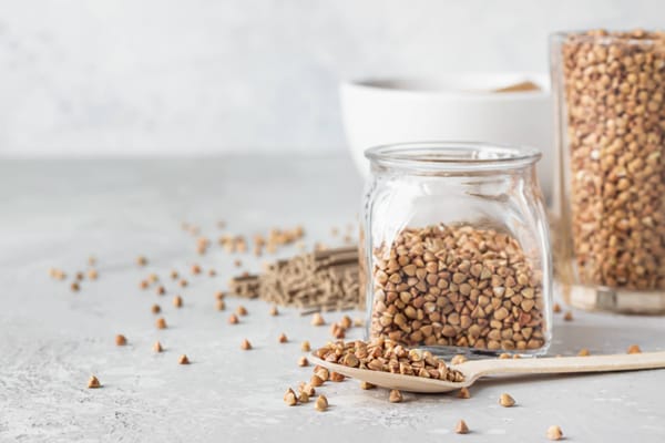 Bowl with gluten free buckwheat flour and buckwheat grains in glass and soba noodles
