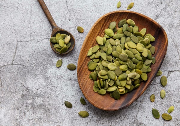Wooden plate with pumpkin seeds on a gray concrete table