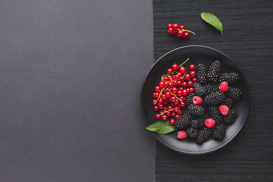 Flat lay plate of fresh berries on wooden table