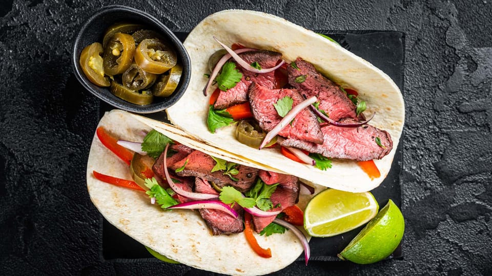 Lupe Tortilla fajita with meat, cilantro, jalapenos, and onion