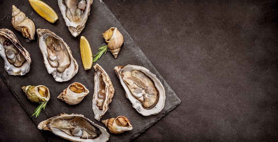 Raw oysters with cooked snails on black platter