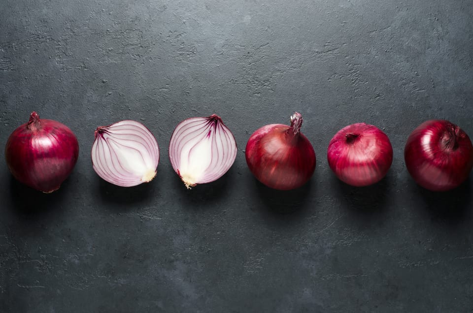 Red onion whole and sliced on black background