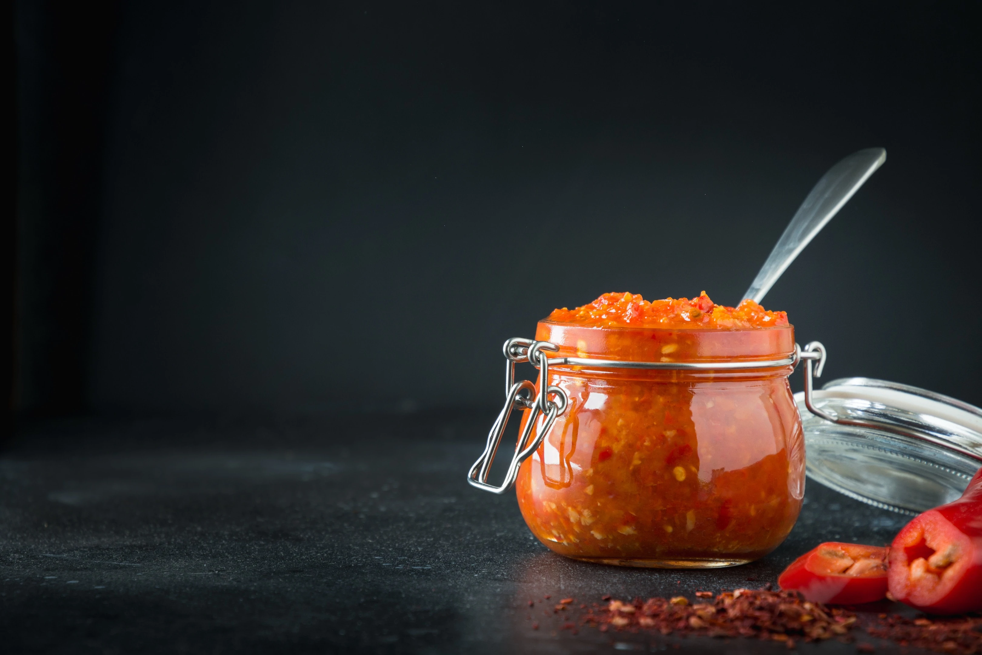 Adjika sauce in glass jar and fresh chili pepper