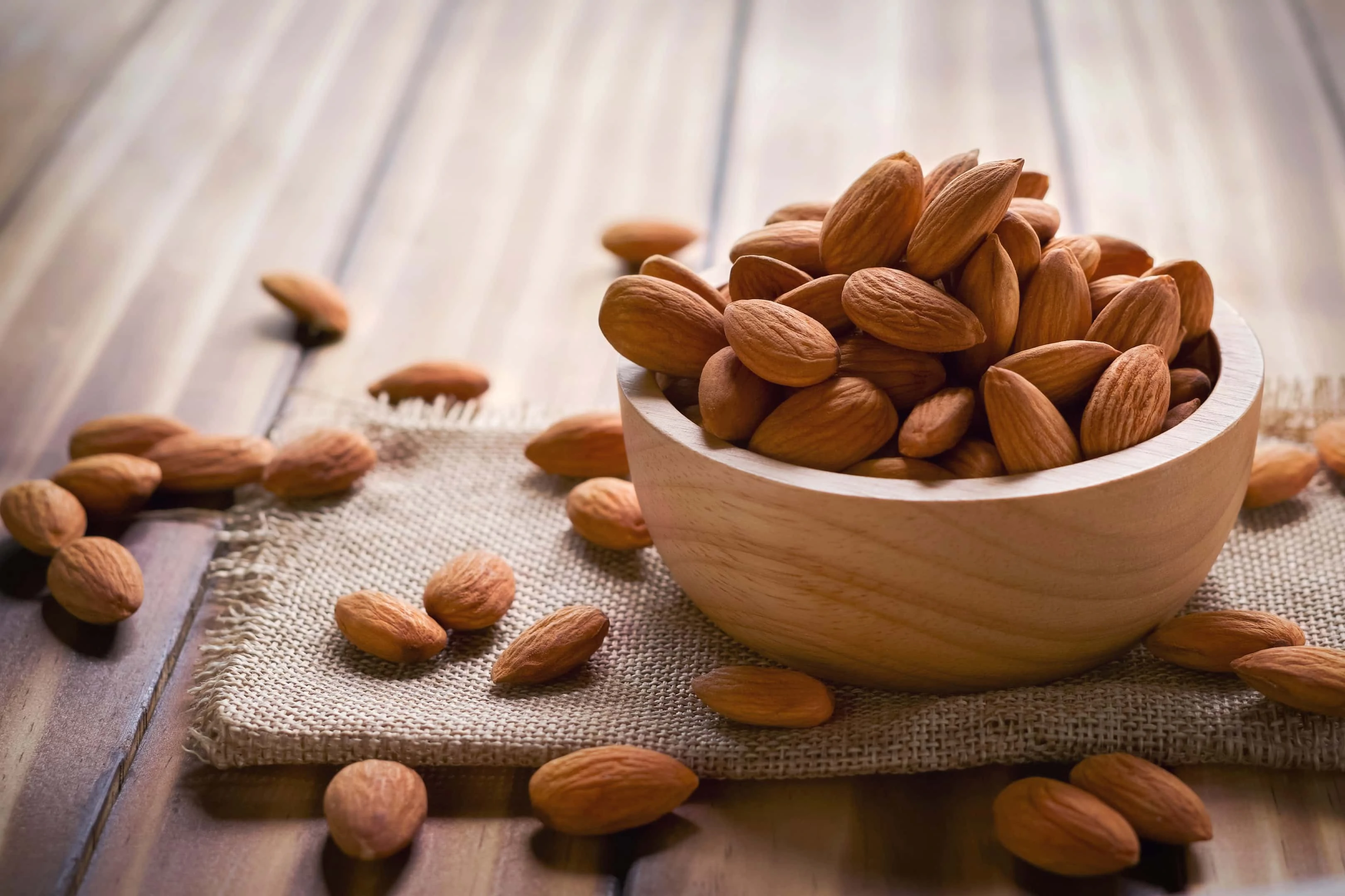Almonds in wooden bowl on wooden table