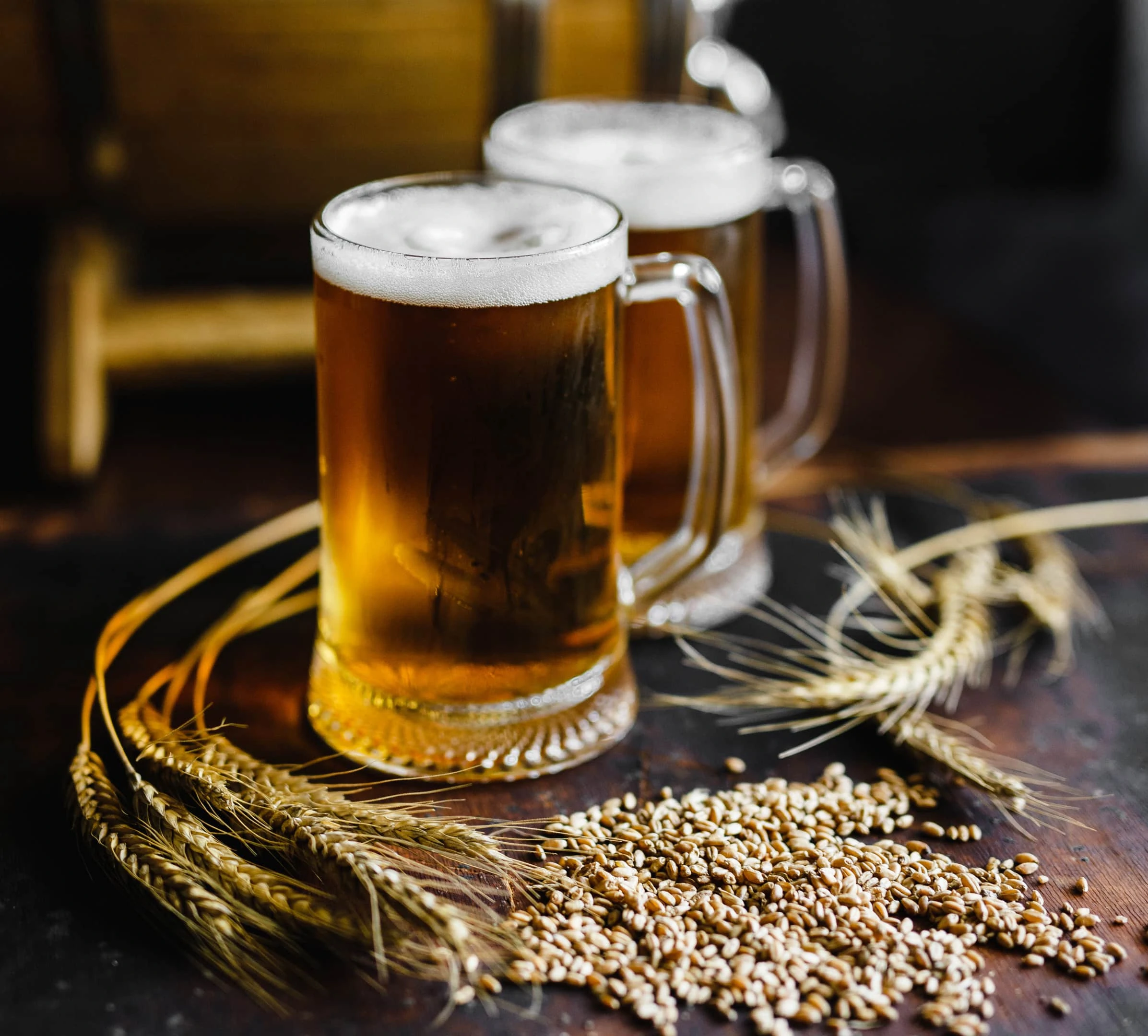 Beer glasses with wheat and brewing barrel