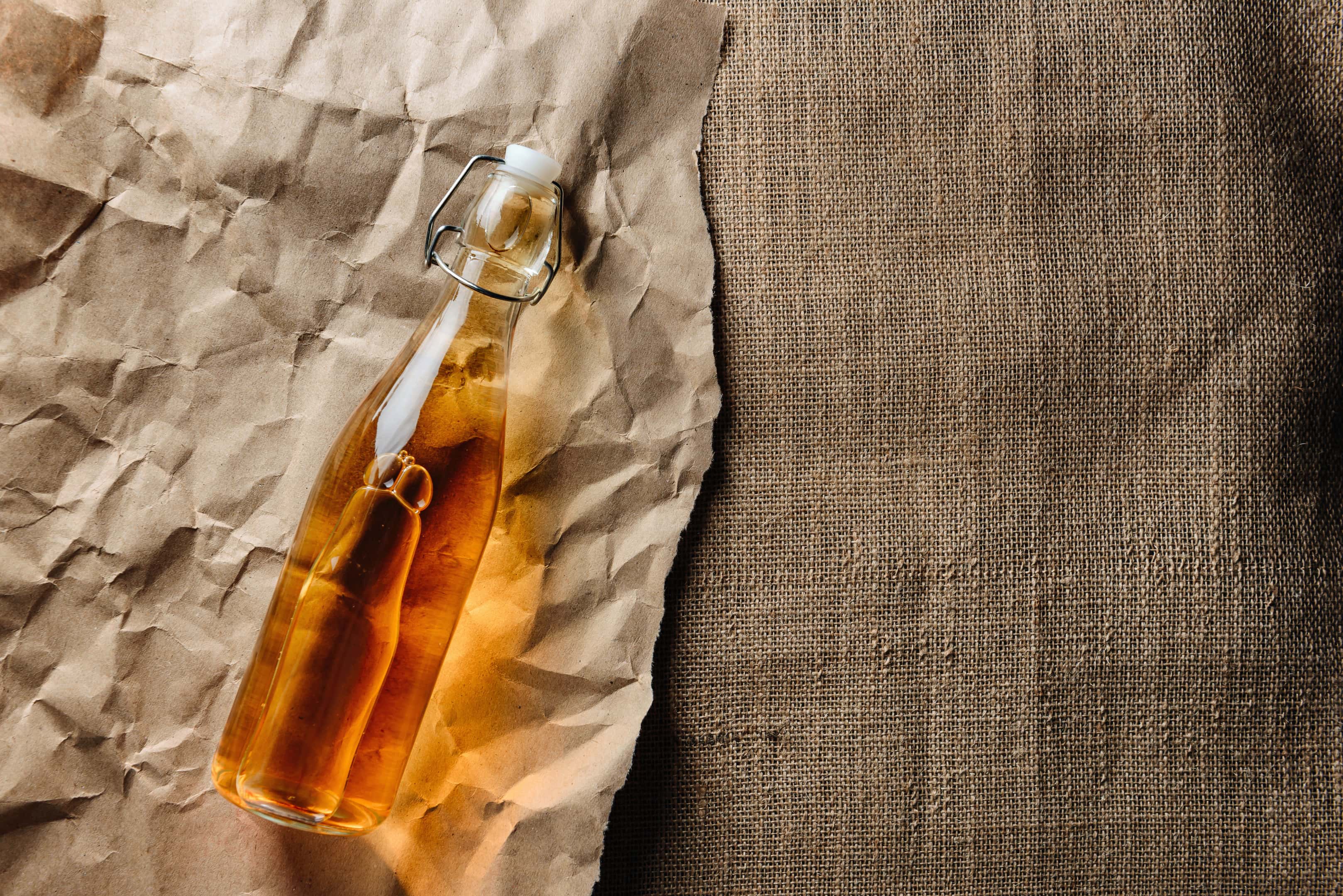 A bottle of homemade champagne vinegar lies on kraft paper