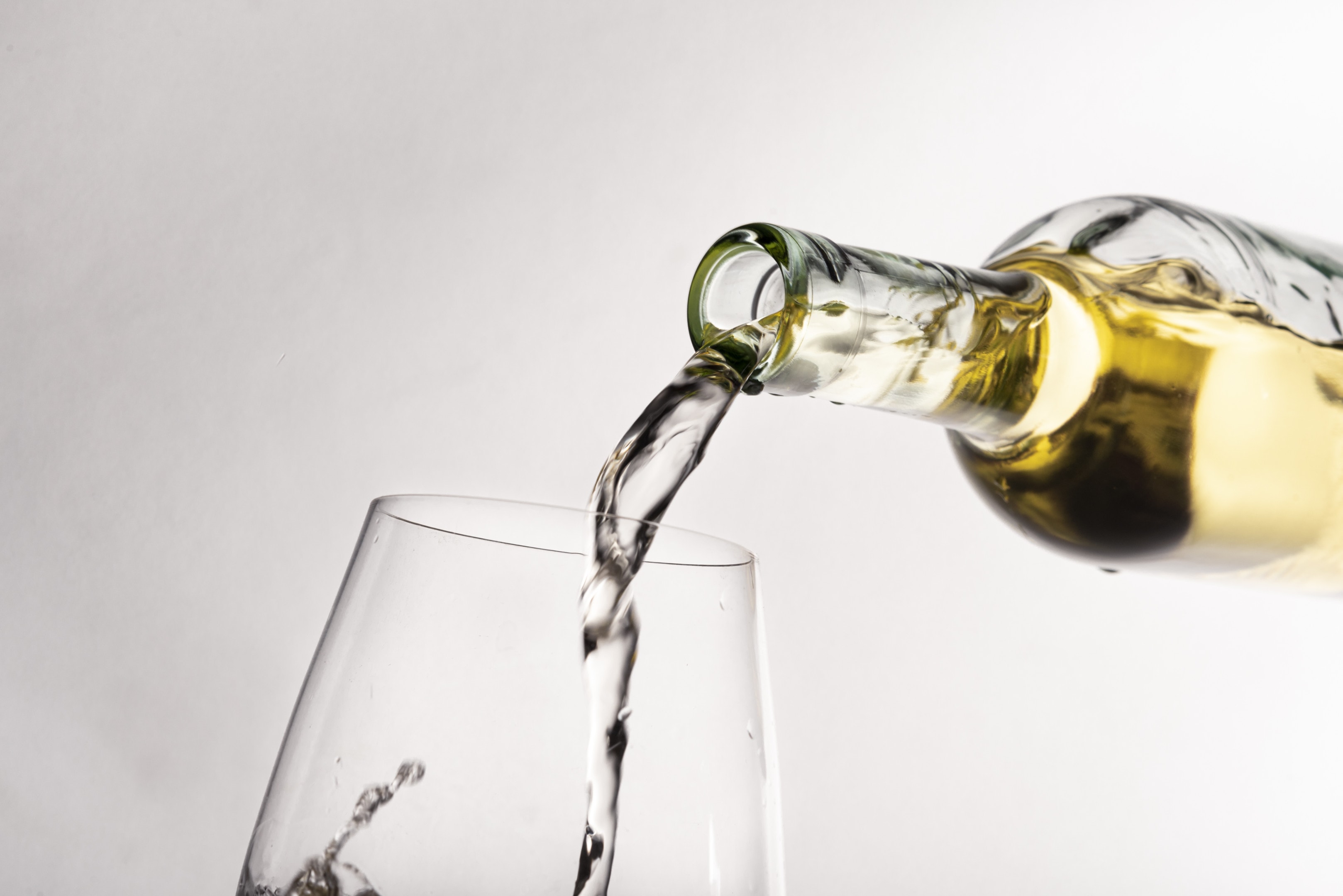 Close up bottle pouring white wine into wine glass