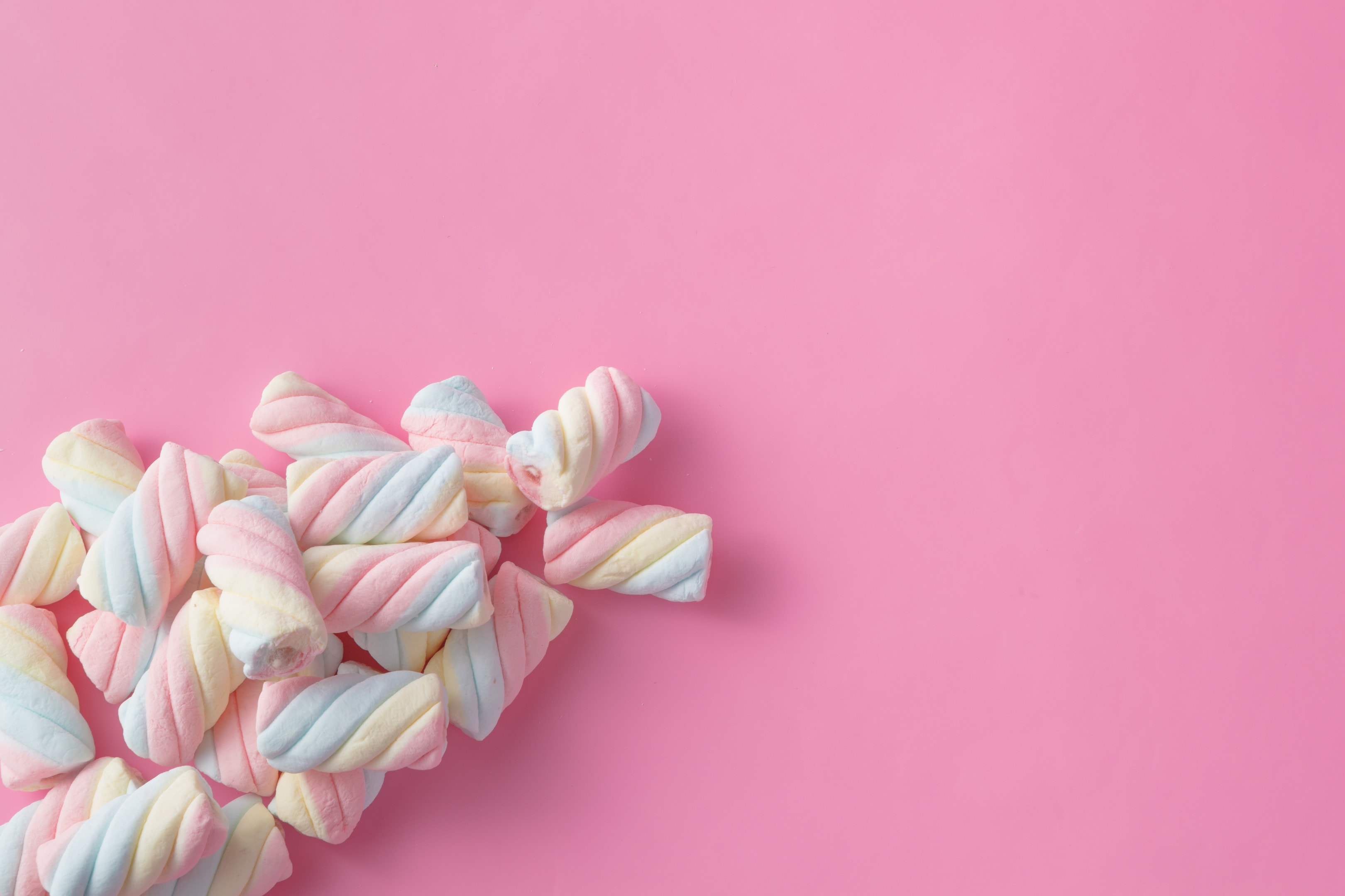 Colored twisted marshmallow on pink background