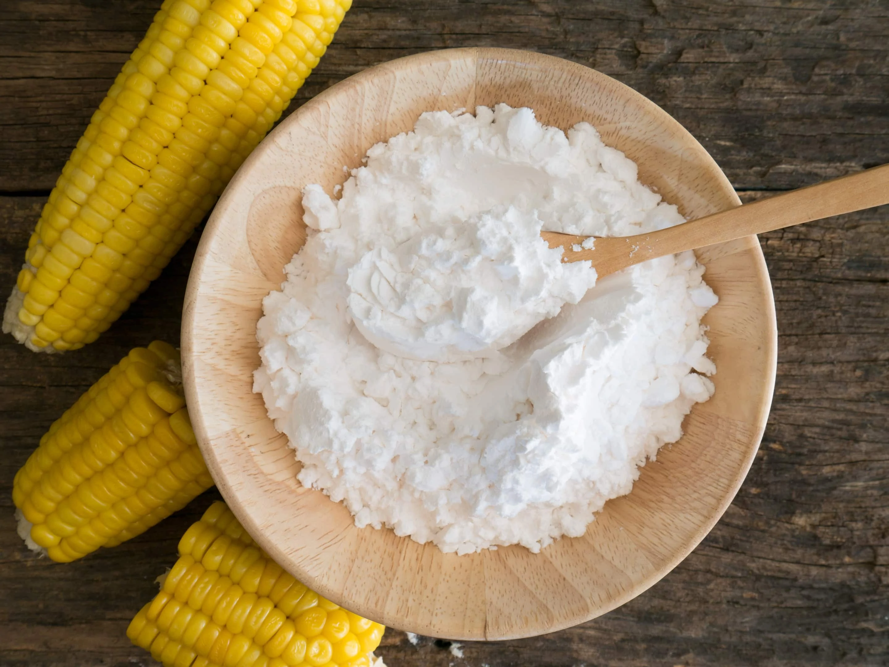 Corn flour in wooden bowl with fresh corn