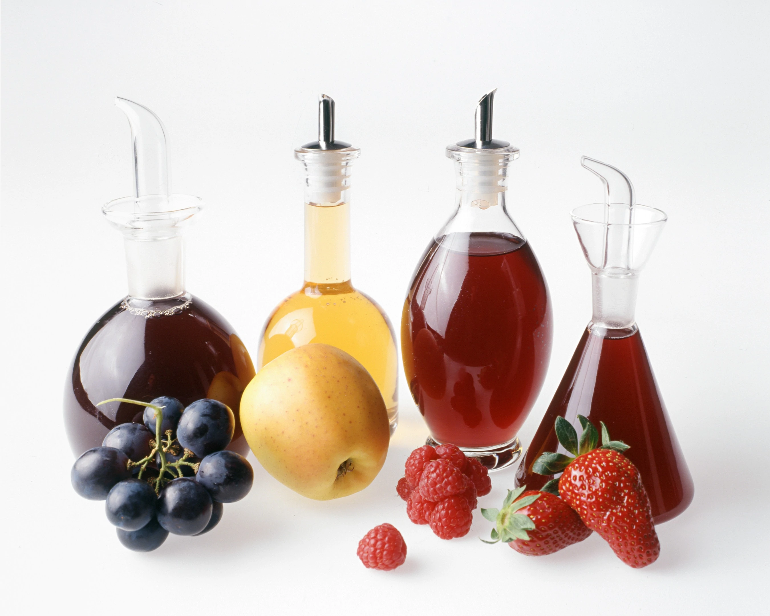 Four fruit vinegars bottles white background
