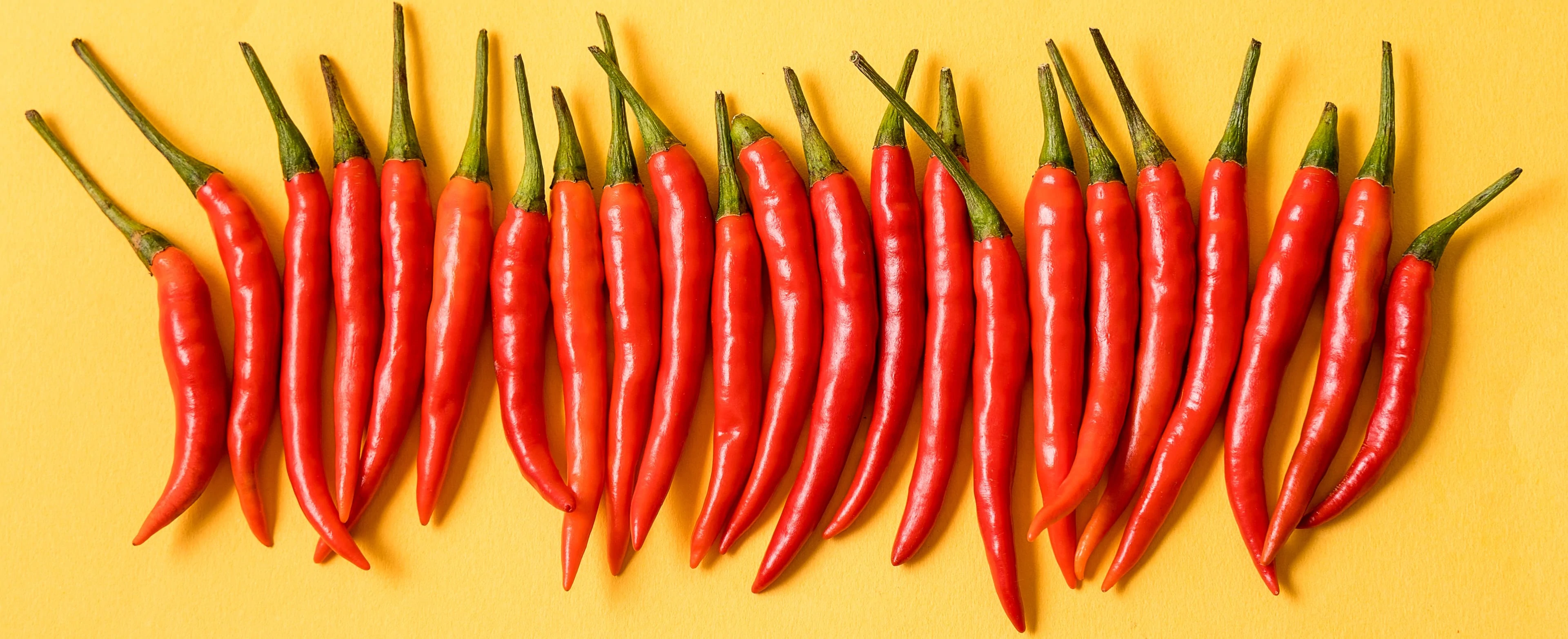 Fresh red thai peppers on yellow background