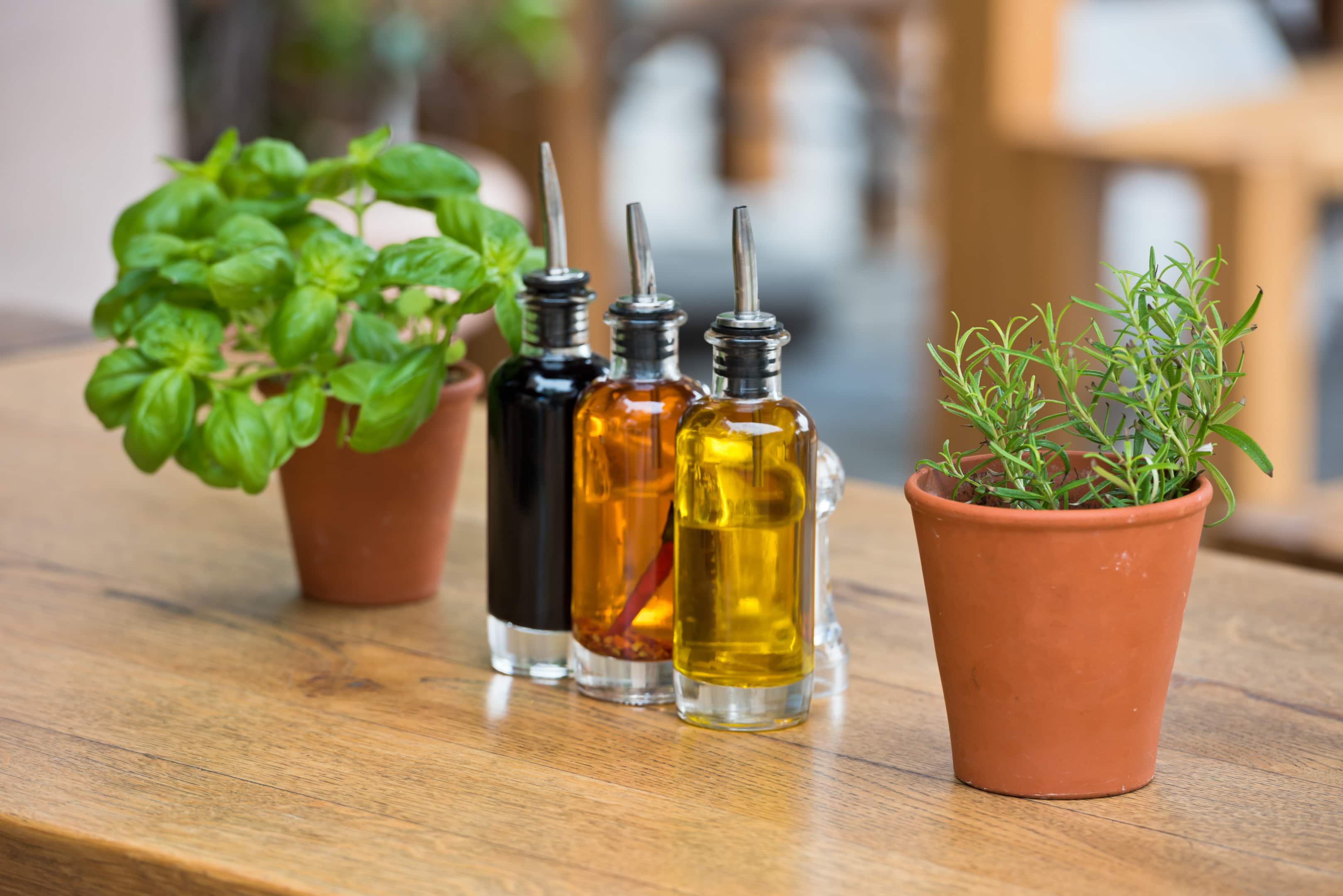 Herb vinegars with fresh herbs on wooden table