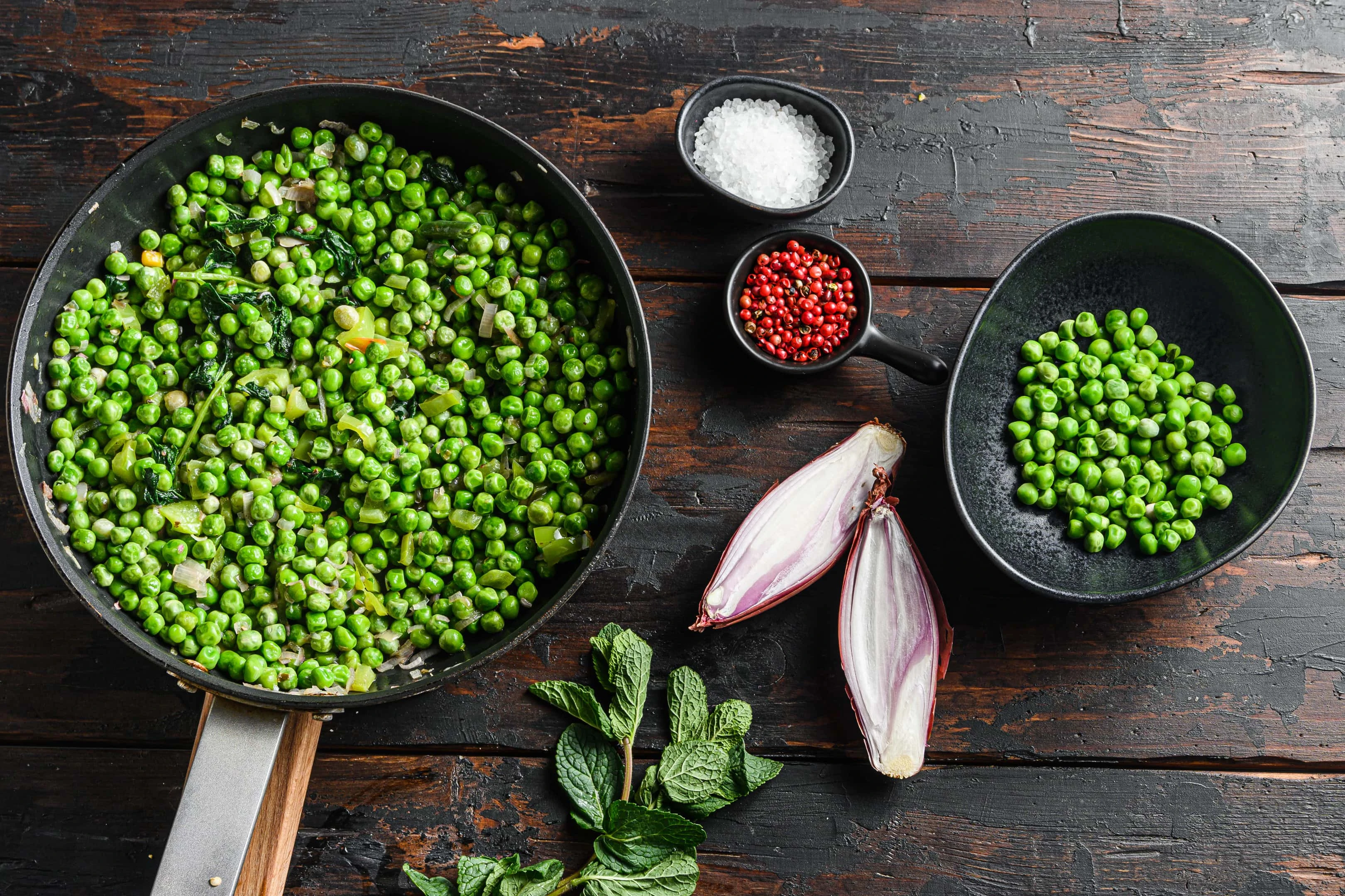 Large pan of cooked peas on wooden table