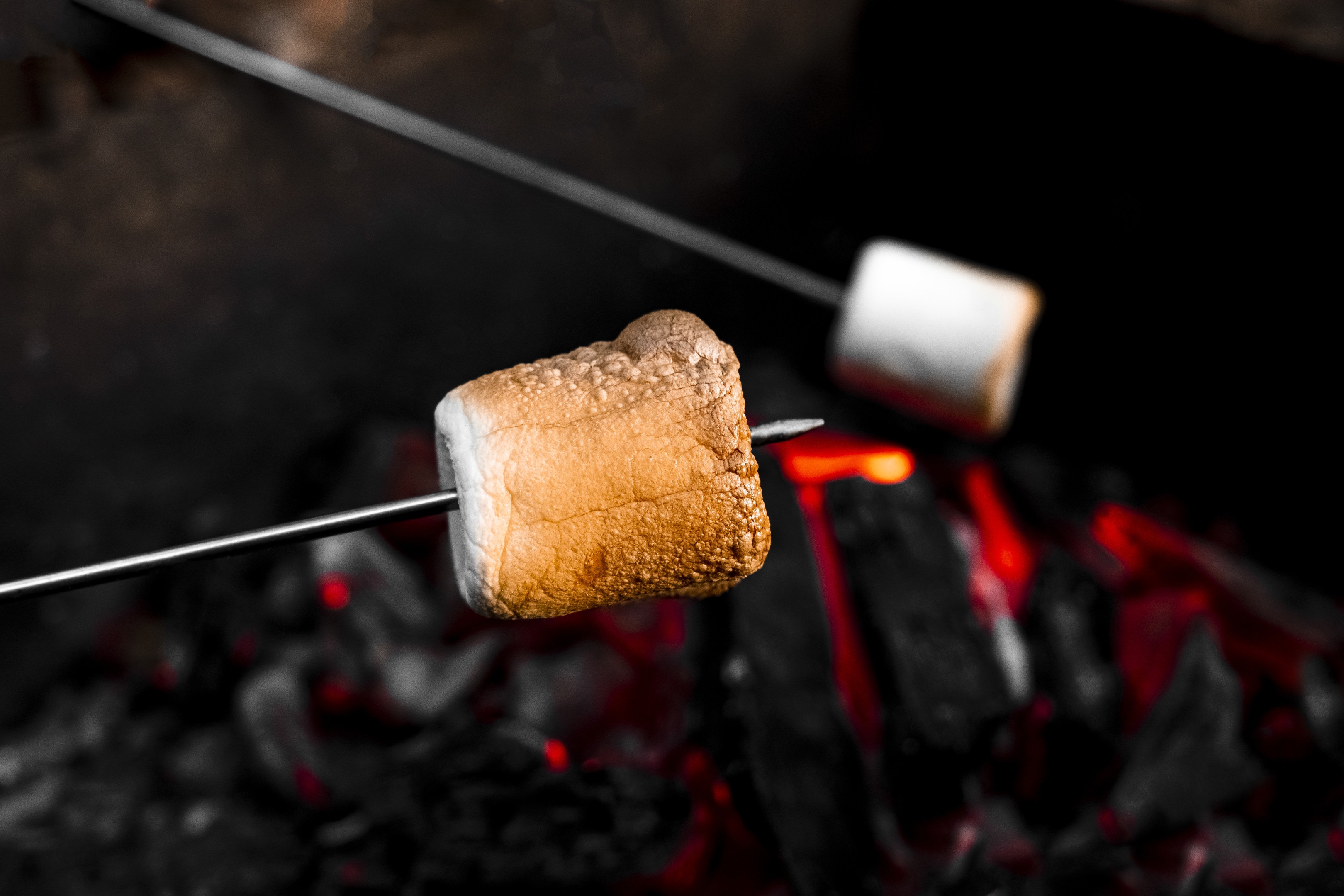Marshmallow on a stick being roasted over a camping fire