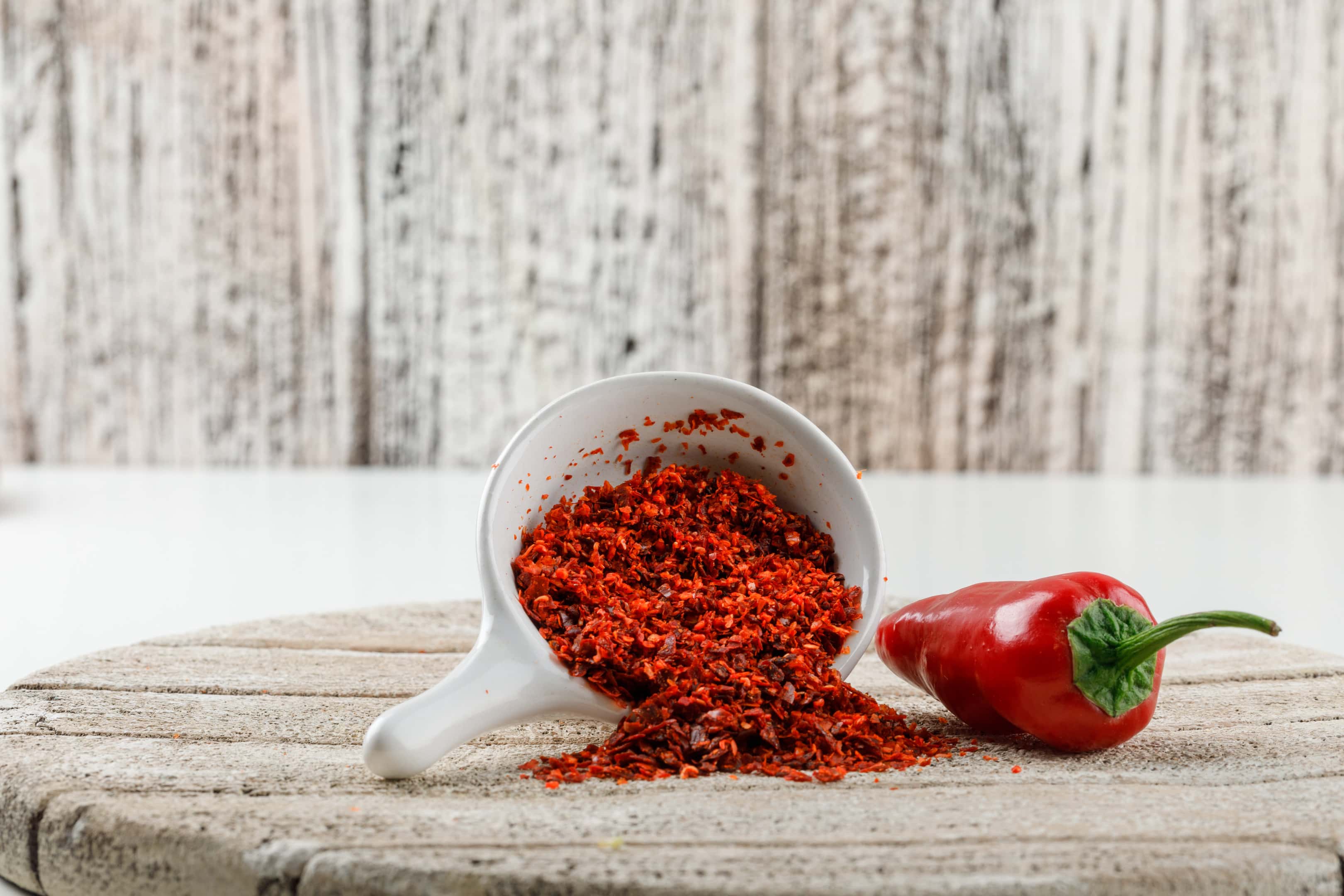 Paprika powder with red paprika pepper on wooden board