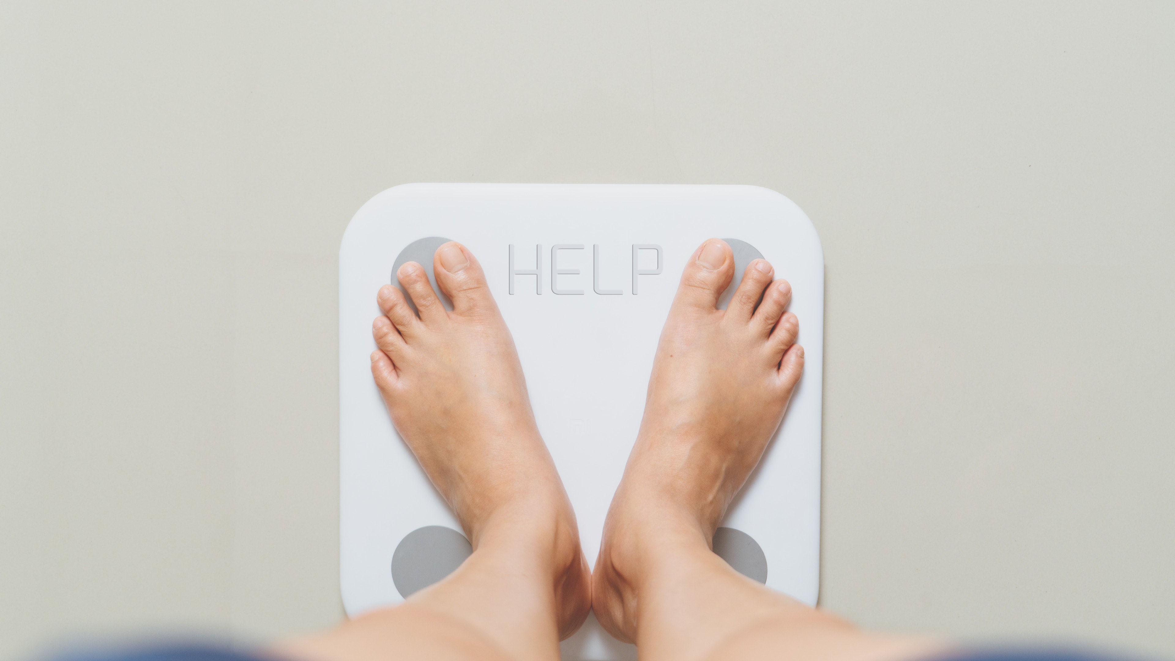 Person standing on white scales with the word help