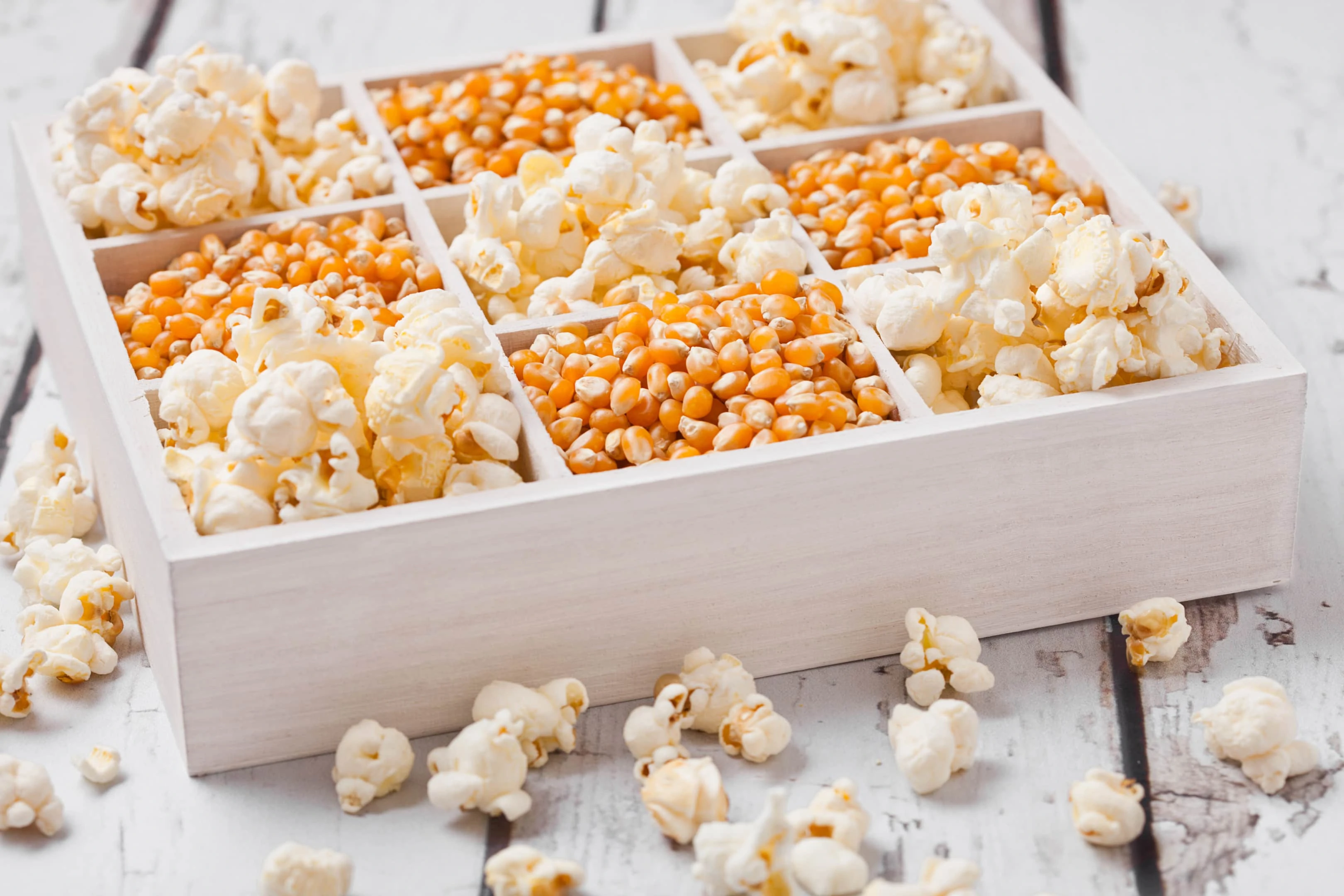Raw corn seeds and popcorn in white wooden box