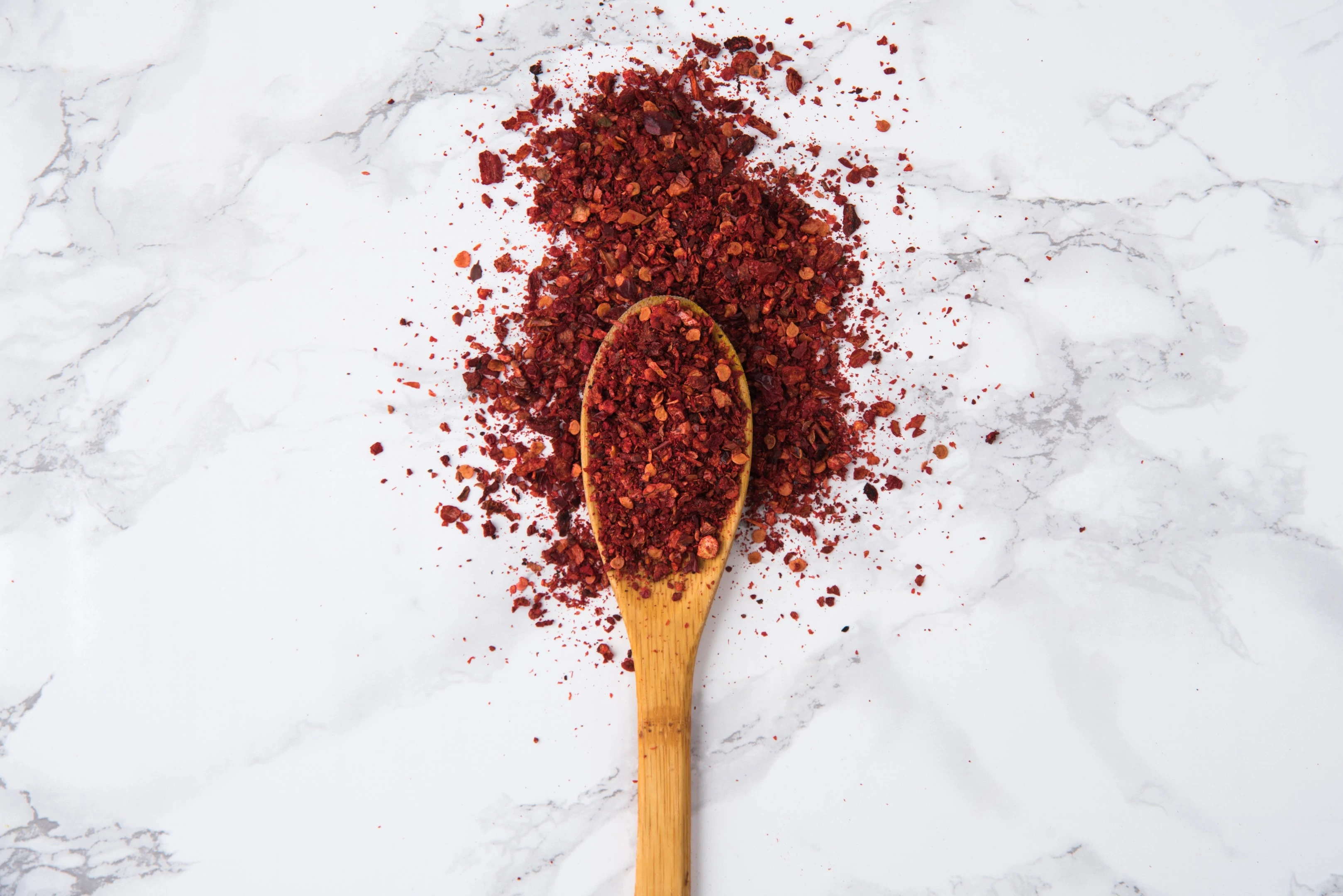 Red hot chilli pepper crushed flakes on wooden spoon