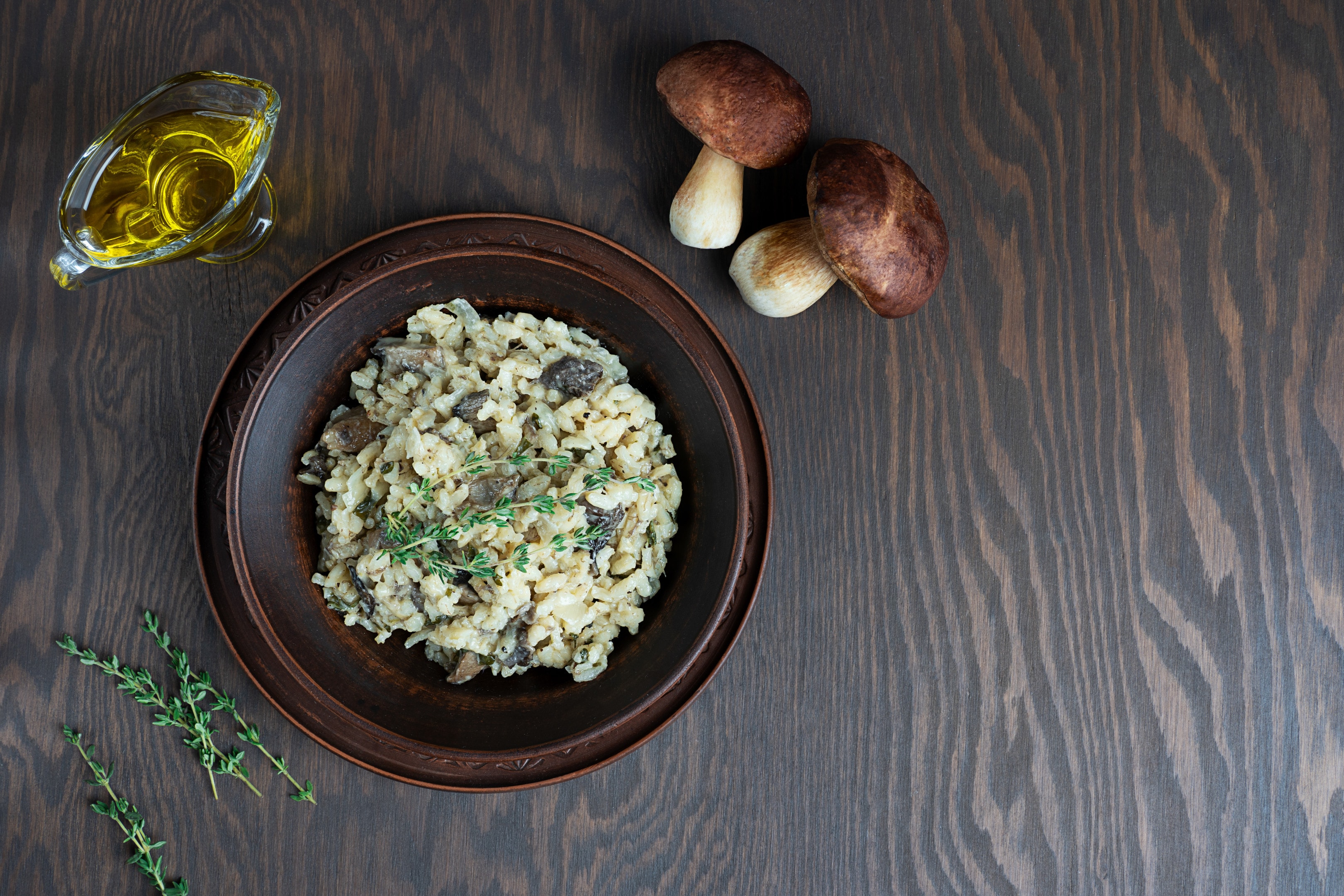 Risotto with arborio rice broth mushrooms thyme on wooden table