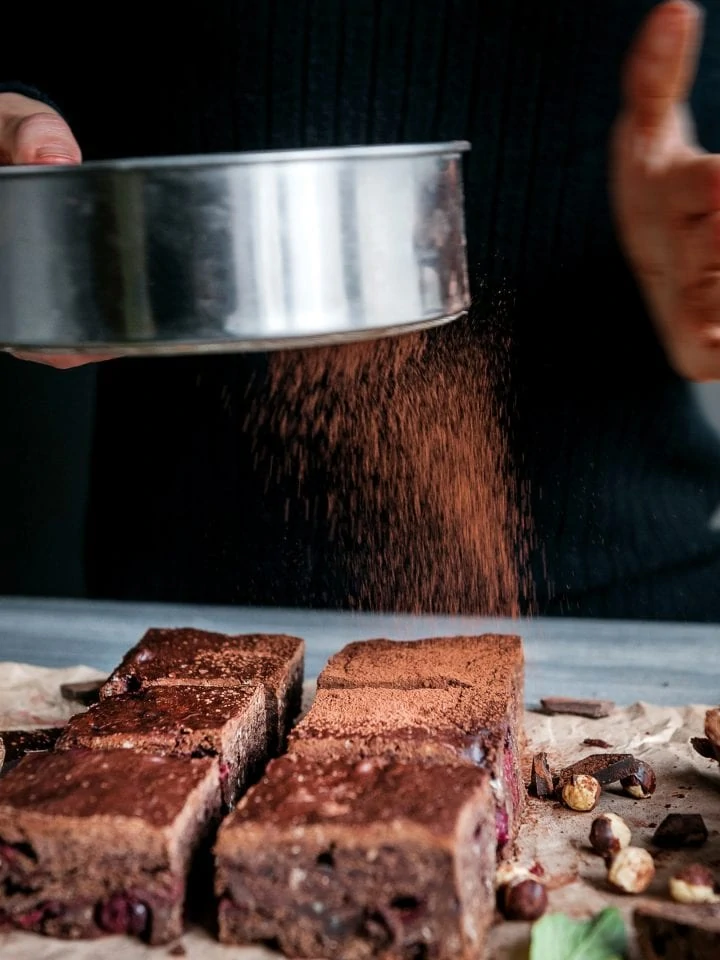 Sprinkling cacao on homemade chocolate chickpea brownie vegan and gluten-free