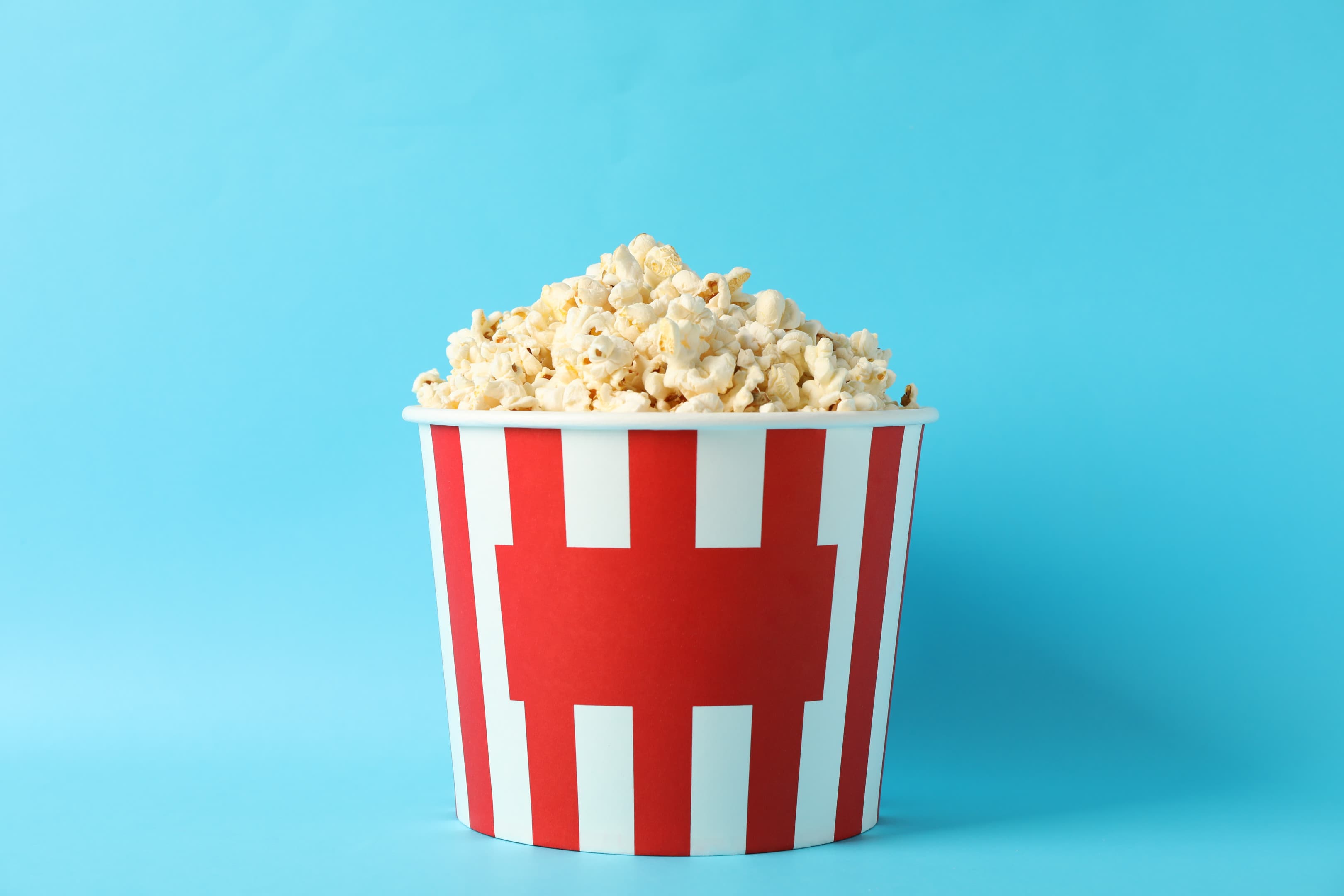 Striped bucket with popcorn on blue background
