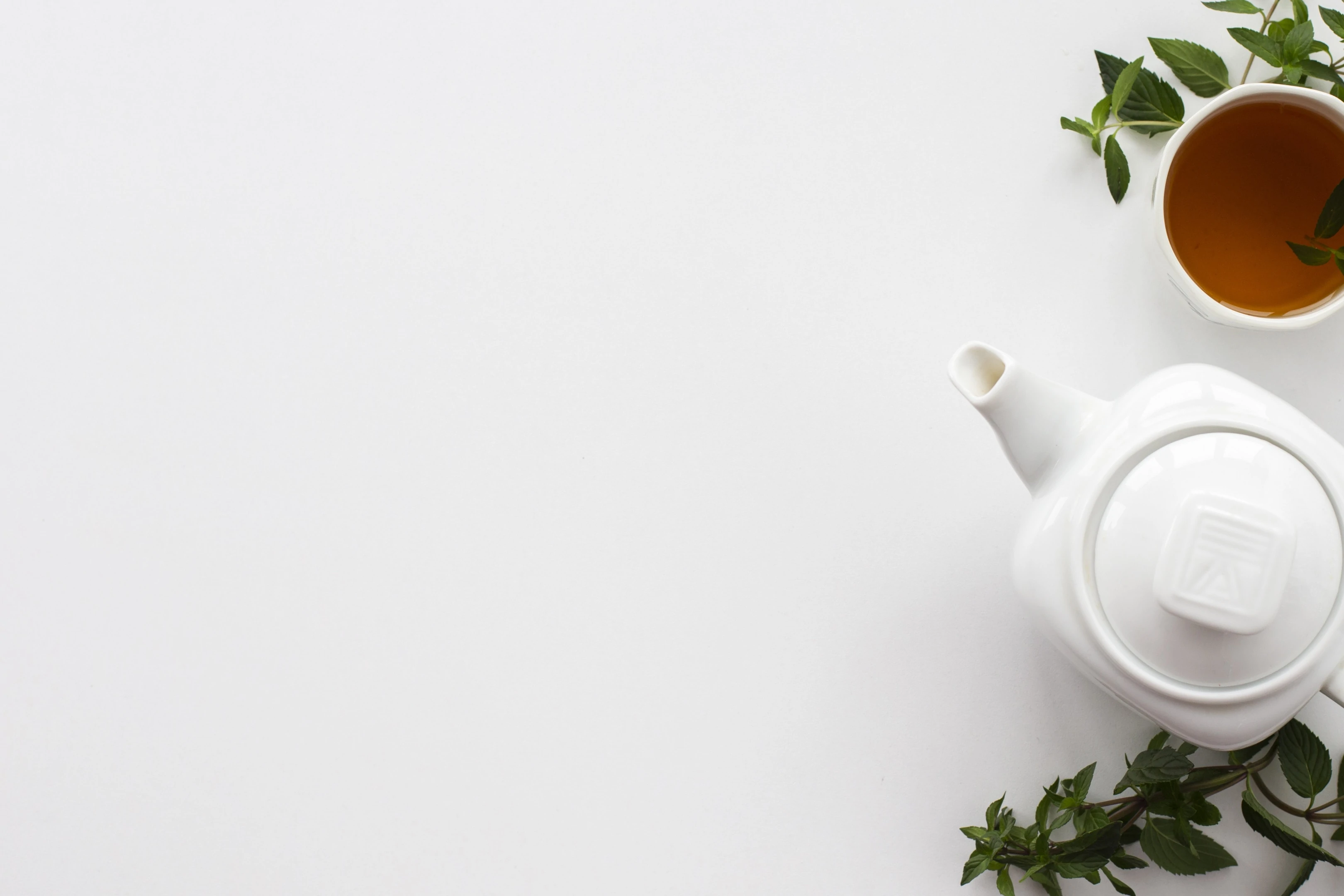 Teapot and cup of white tea with mint leaves
